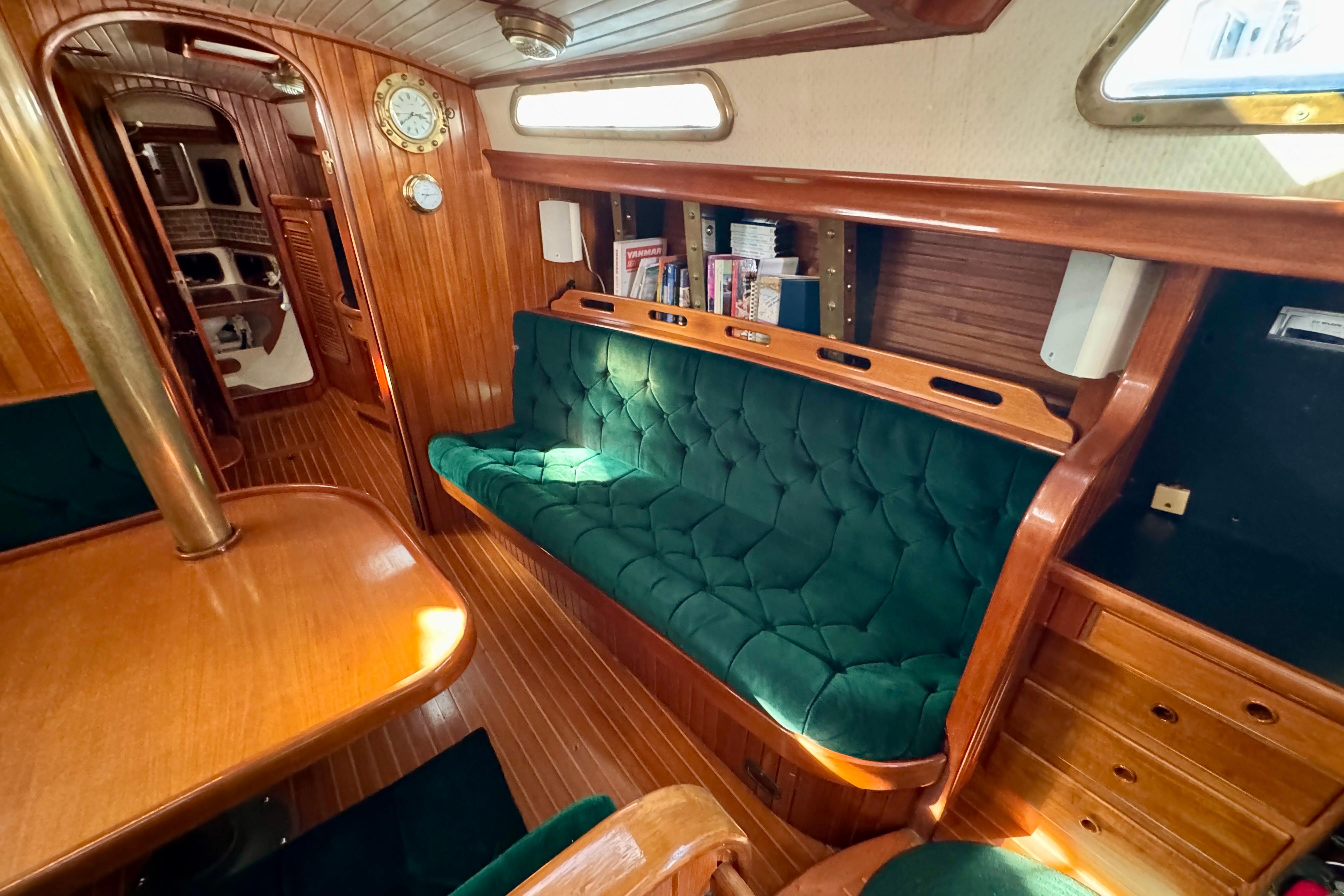 Interior of 1988 Hans Christian Christina yacht with green seating and wooden finishes.