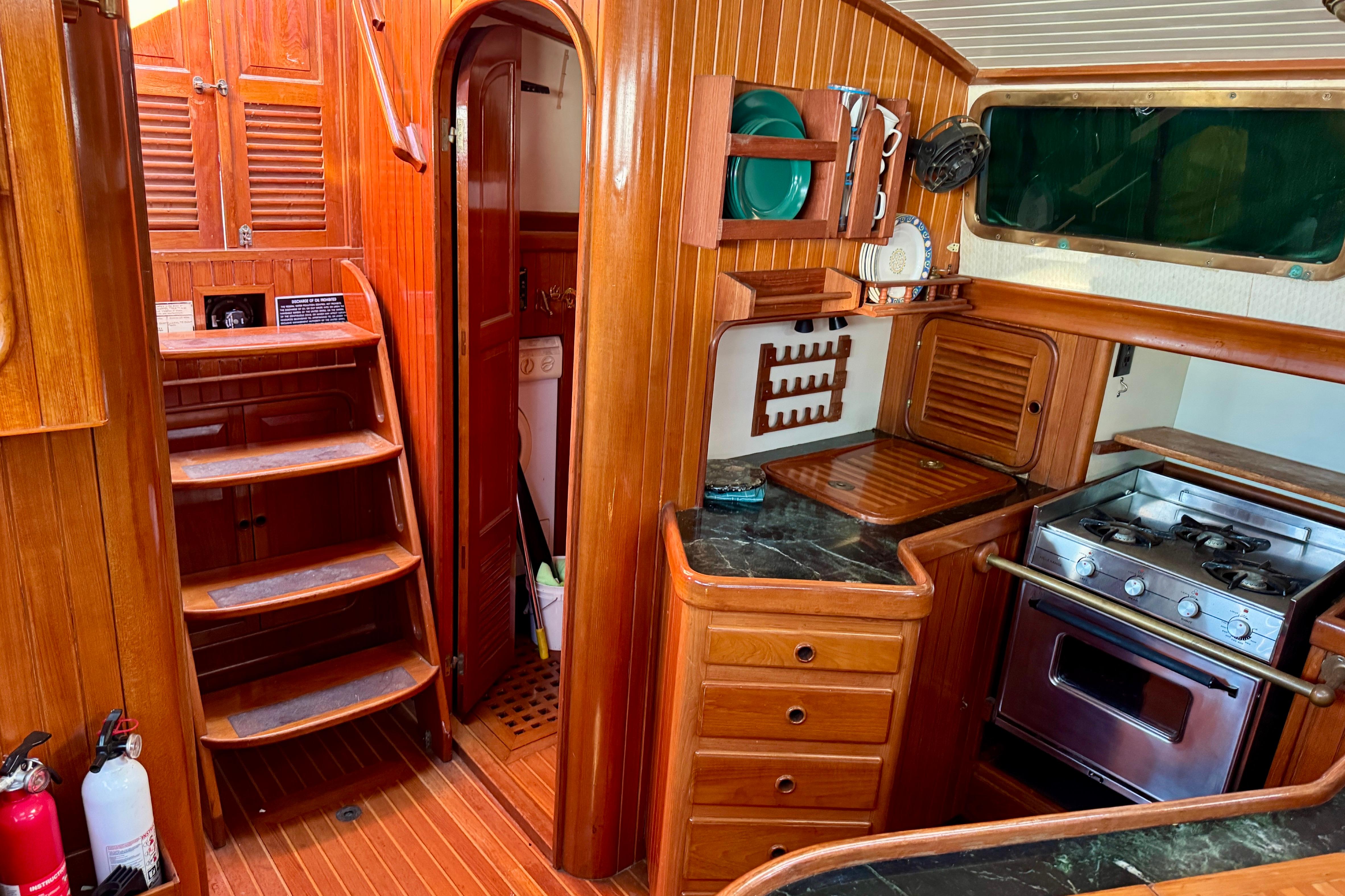 Interior of 1988 Hans Christian Christina sailboat with wooden cabinetry and compact kitchen.