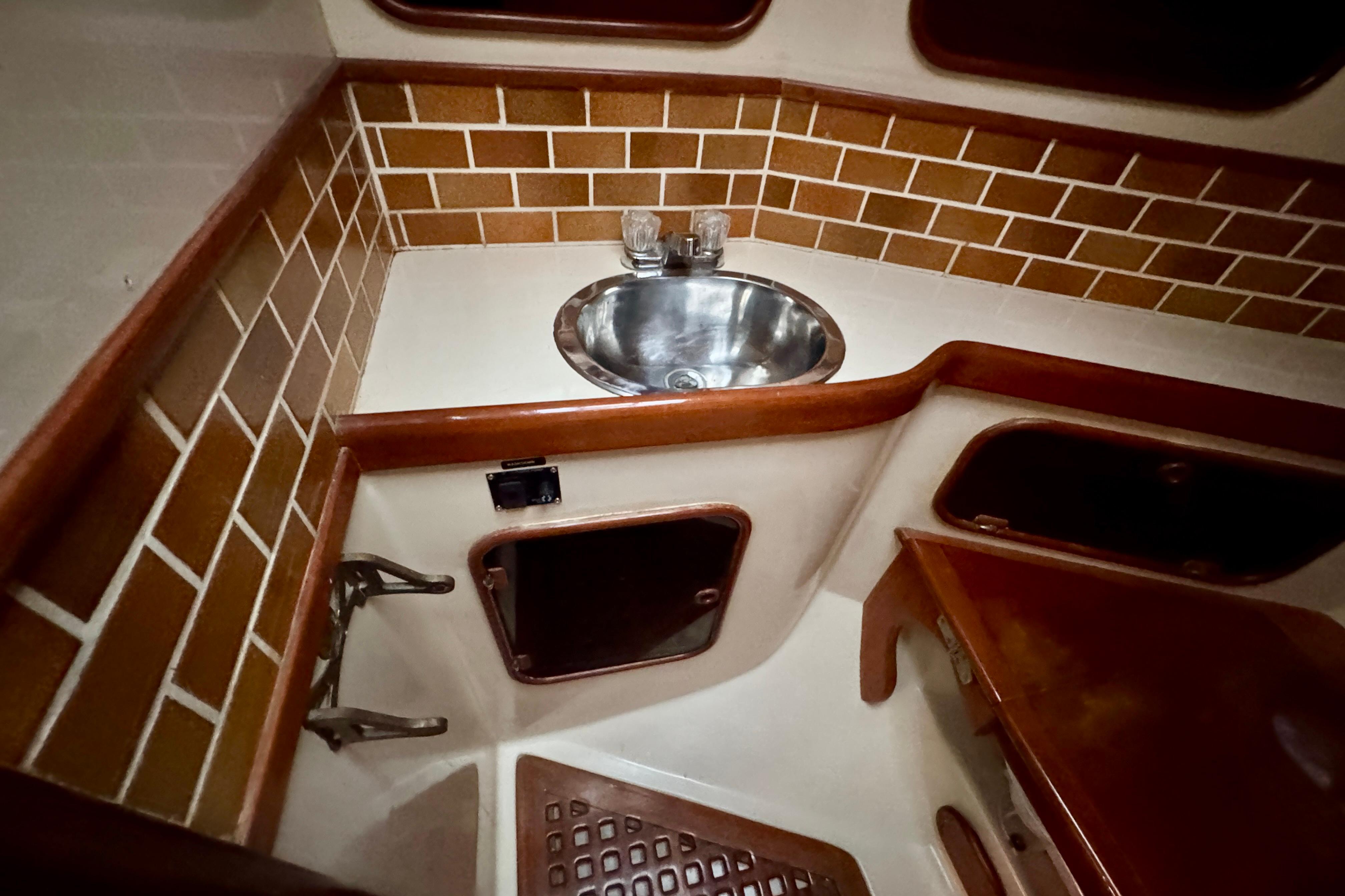 1988 Hans Christian Christina yacht bathroom with sink, wooden accents, and tiled walls.