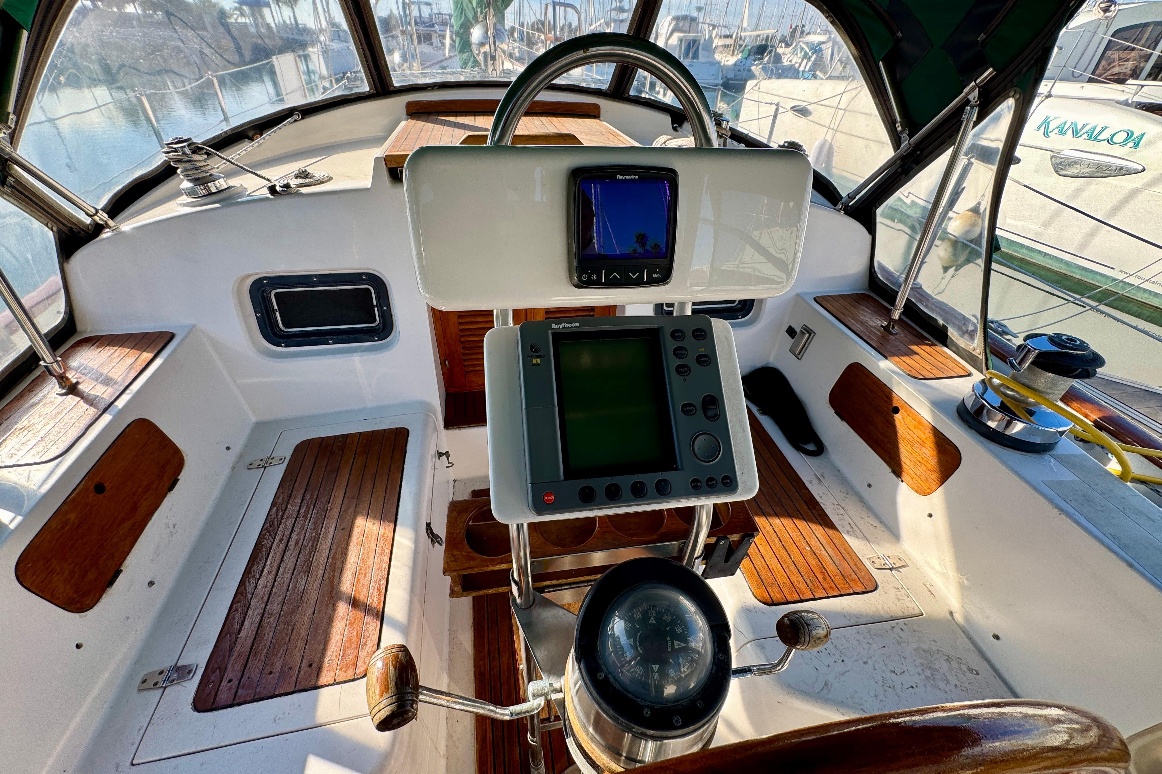 Cockpit of 1988 Hans Christian Christina sailboat with navigation equipment and wooden seating.