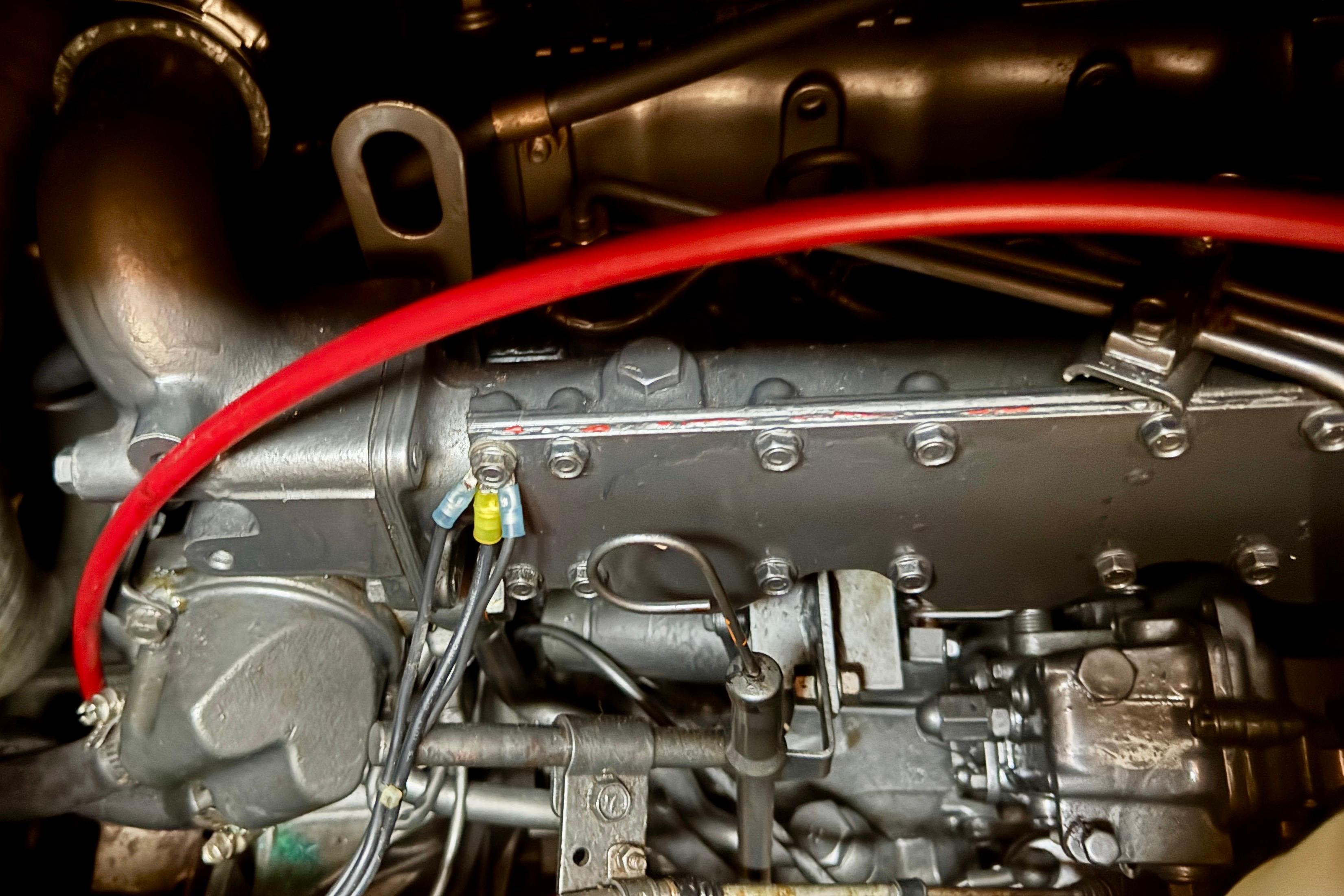 Engine components of a 1988 Hans Christian Christina, featuring red wiring and metallic parts.