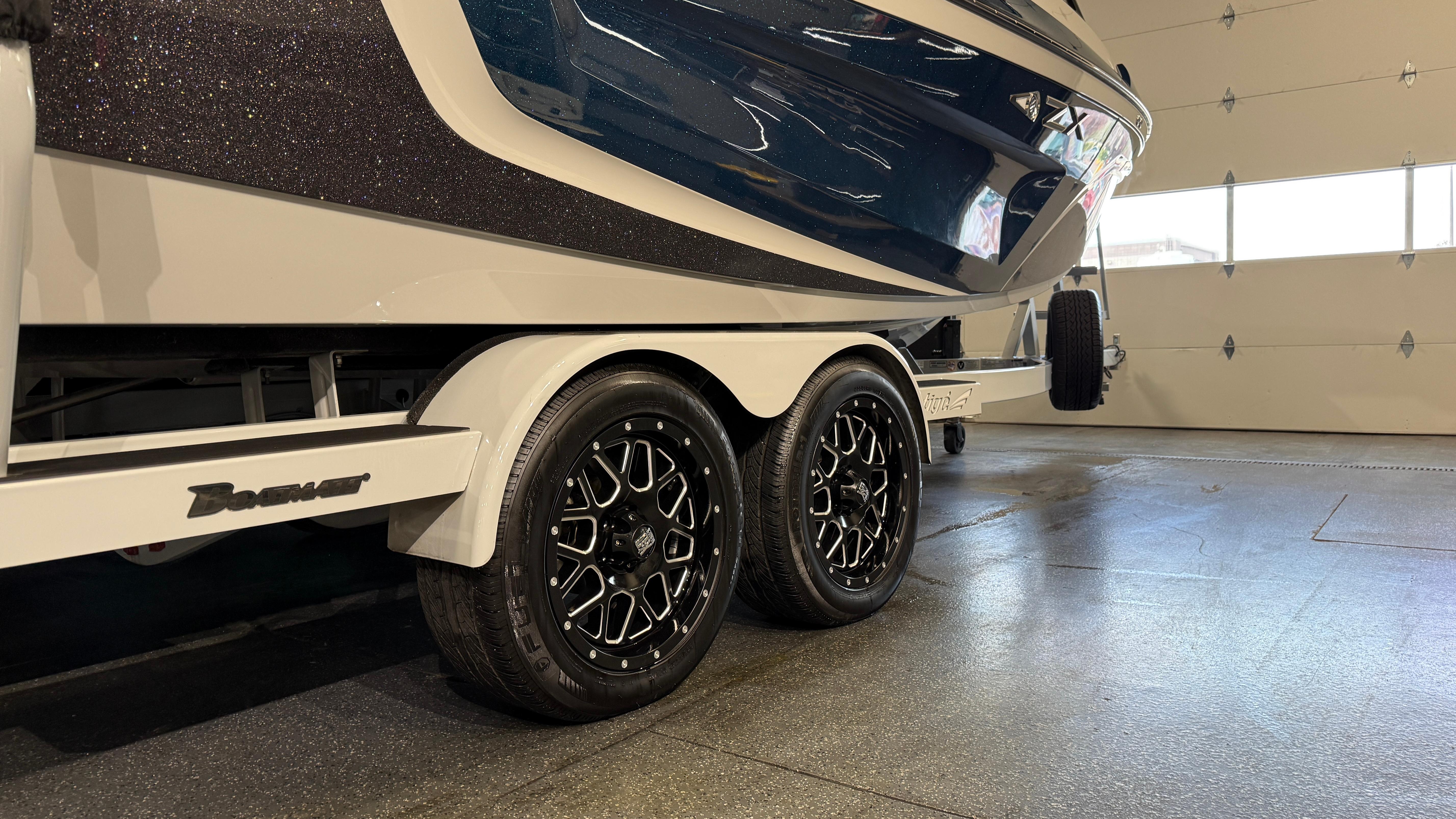 2022 Tigé 23ZX boat on trailer with stylish black wheels in a garage.