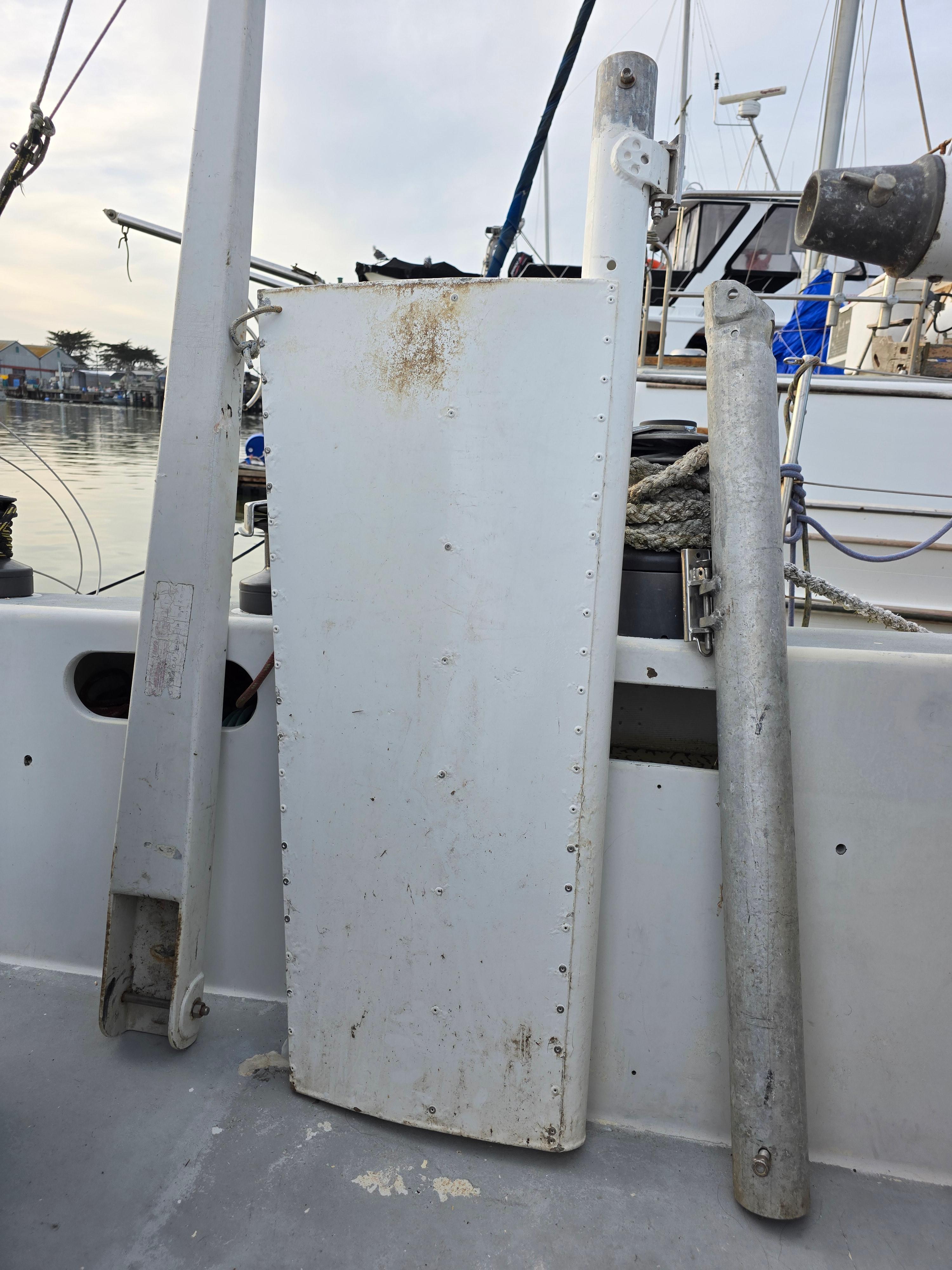 Sailboat parts on deck of 1986 Santa Cruz 50, including rudder and mast components.