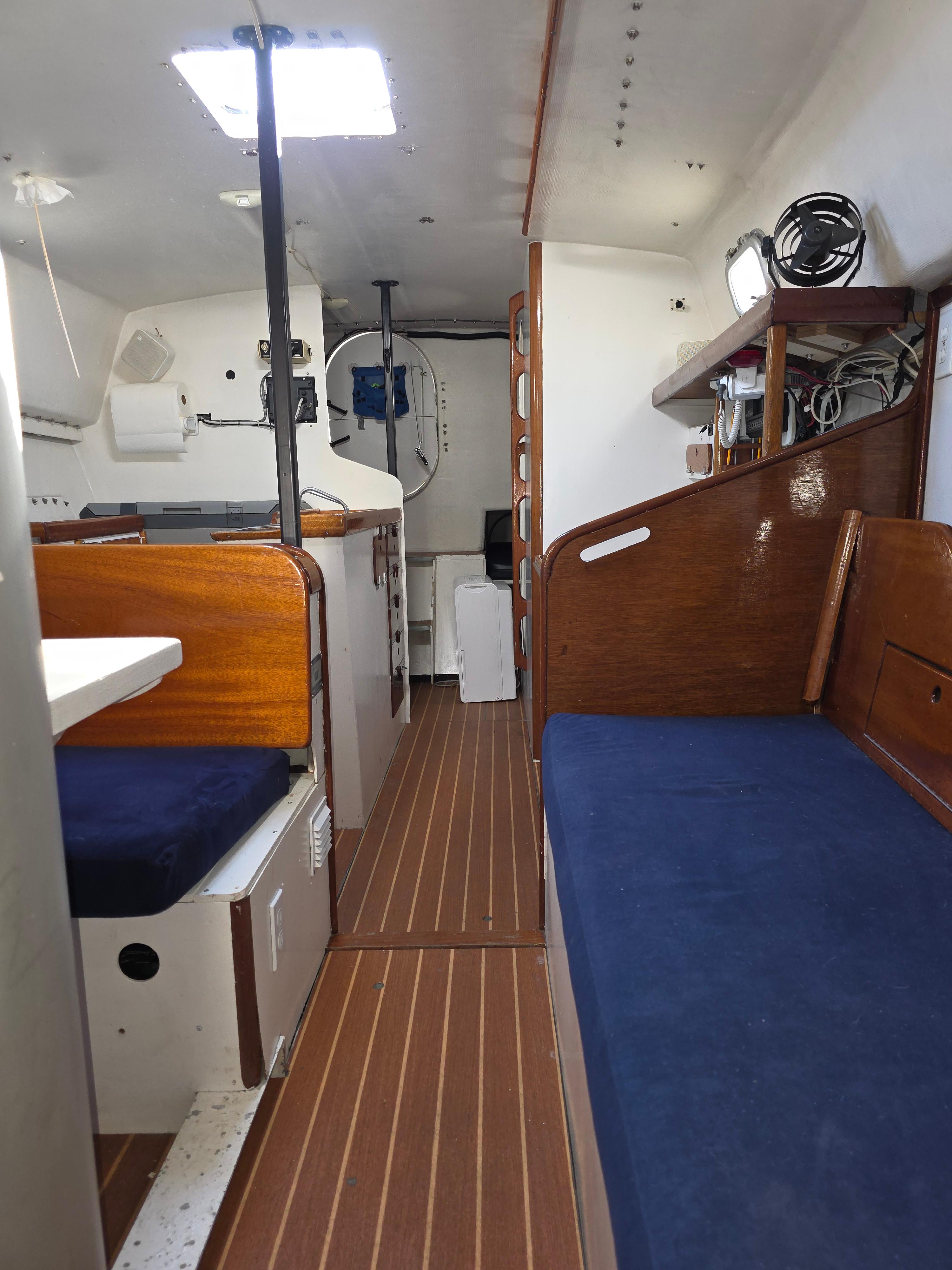 Interior of 1986 Santa Cruz 50 sailboat with wooden finishes and blue seating.
