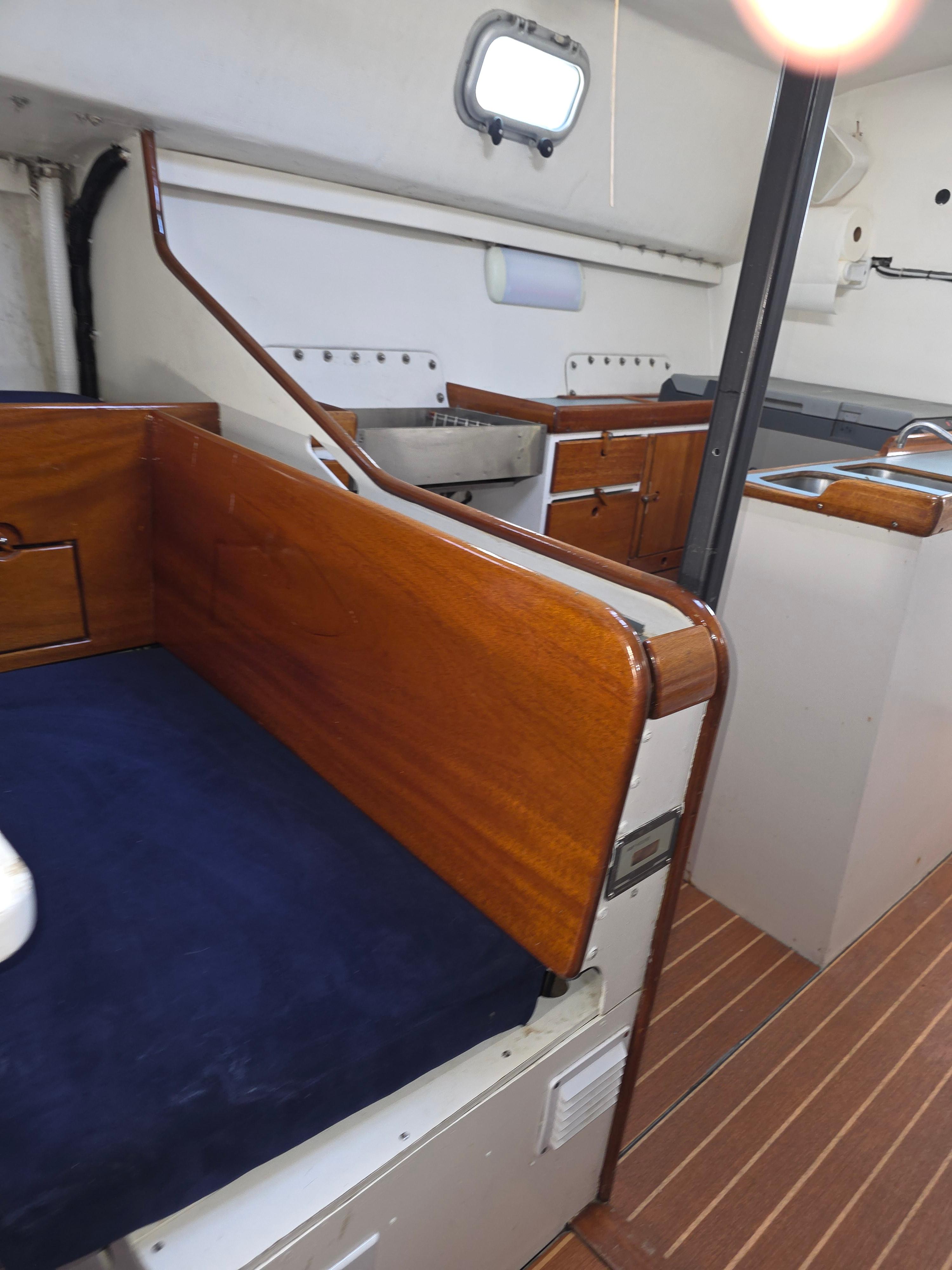 Interior of 1986 Santa Cruz 50 yacht with wooden finishes and compact kitchen area.