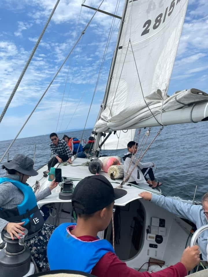 People sailing on a 1986 Santa Cruz 50 yacht under a clear blue sky.
