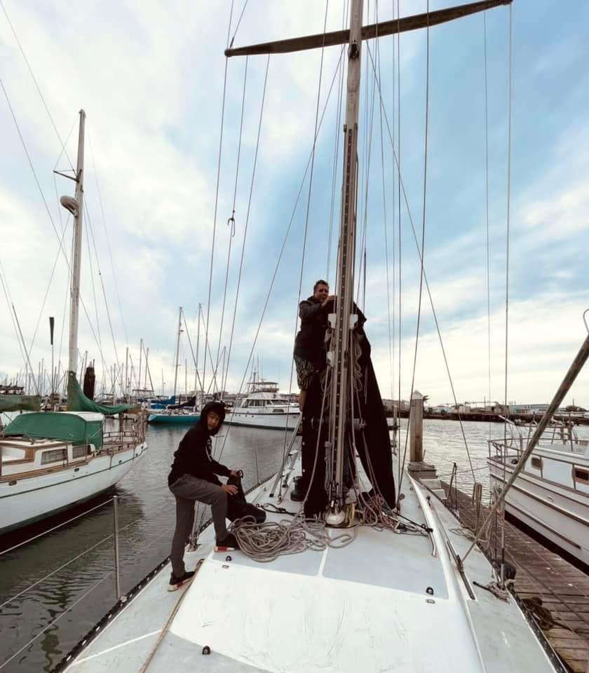 Two people working on a 1986 Santa Cruz 50 sailboat at a marina.