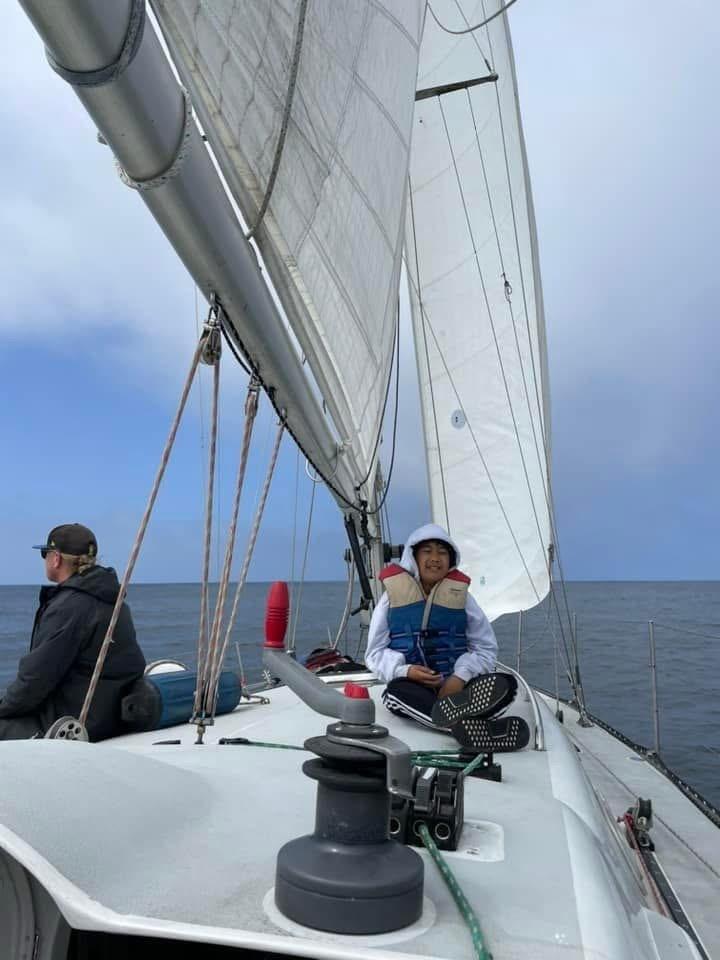 Two people sailing on a 1986 Santa Cruz 50 yacht under clear skies.