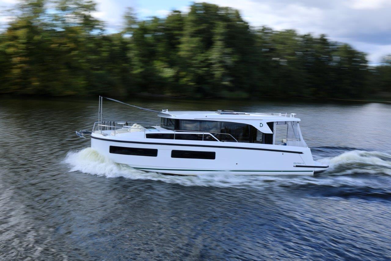 2025 Delphia D11 SEDAN cruising on a scenic river with lush greenery.