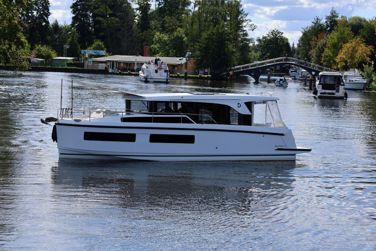 2025 Delphia D11 SEDAN cruising on a scenic river with lush greenery.