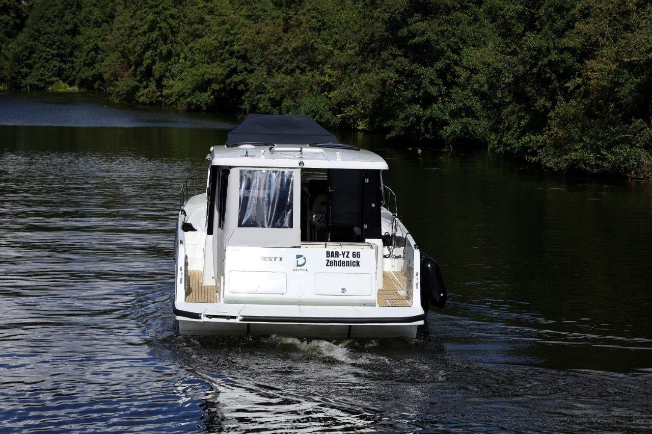 2025 Delphia D11 SEDAN cruising on a serene river surrounded by lush greenery.