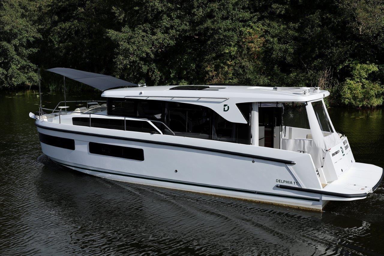 2025 Delphia D11 SEDAN cruising on a serene river, surrounded by lush greenery.