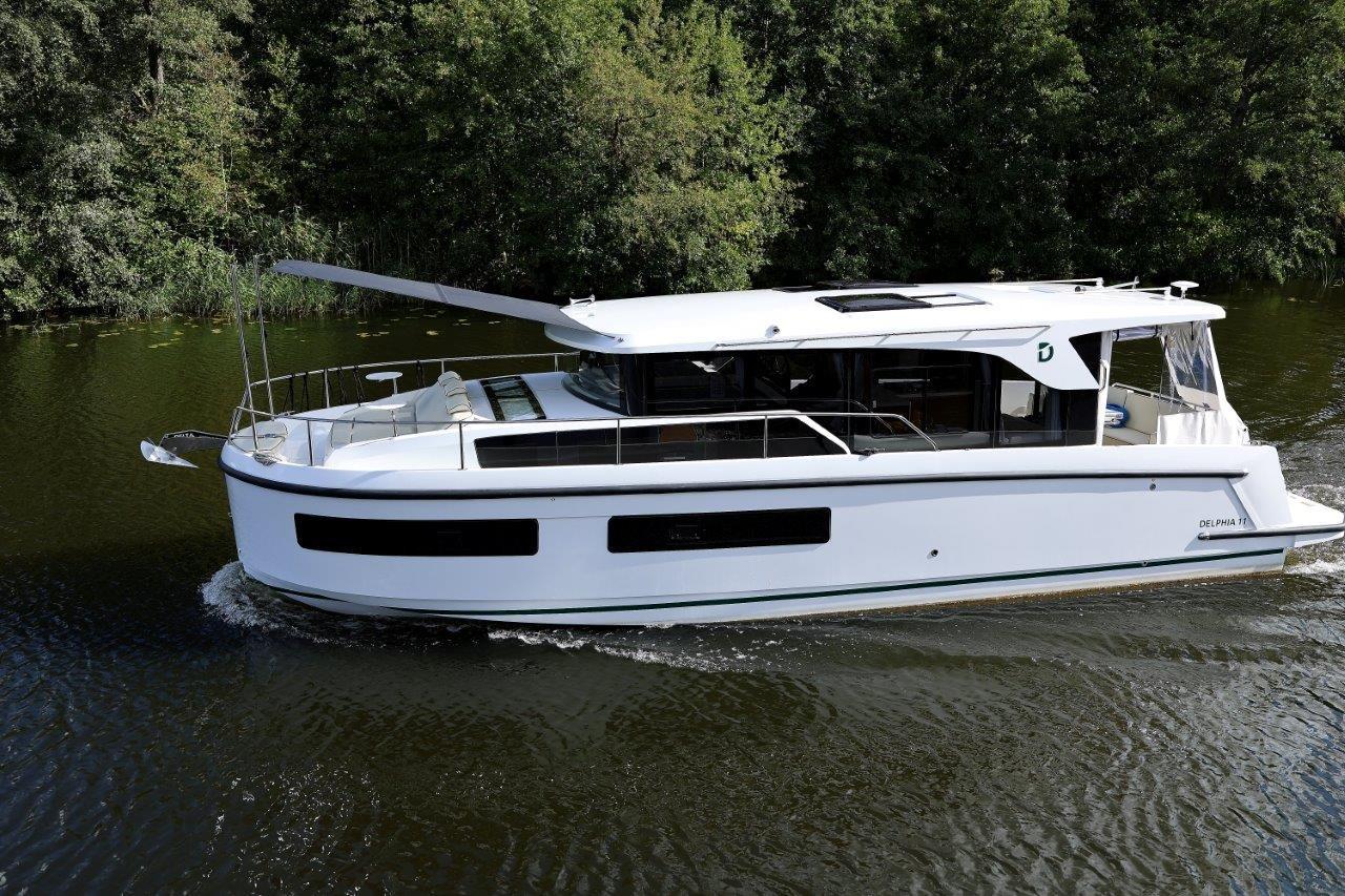 2025 Delphia D11 SEDAN cruising on a serene river, surrounded by lush greenery.