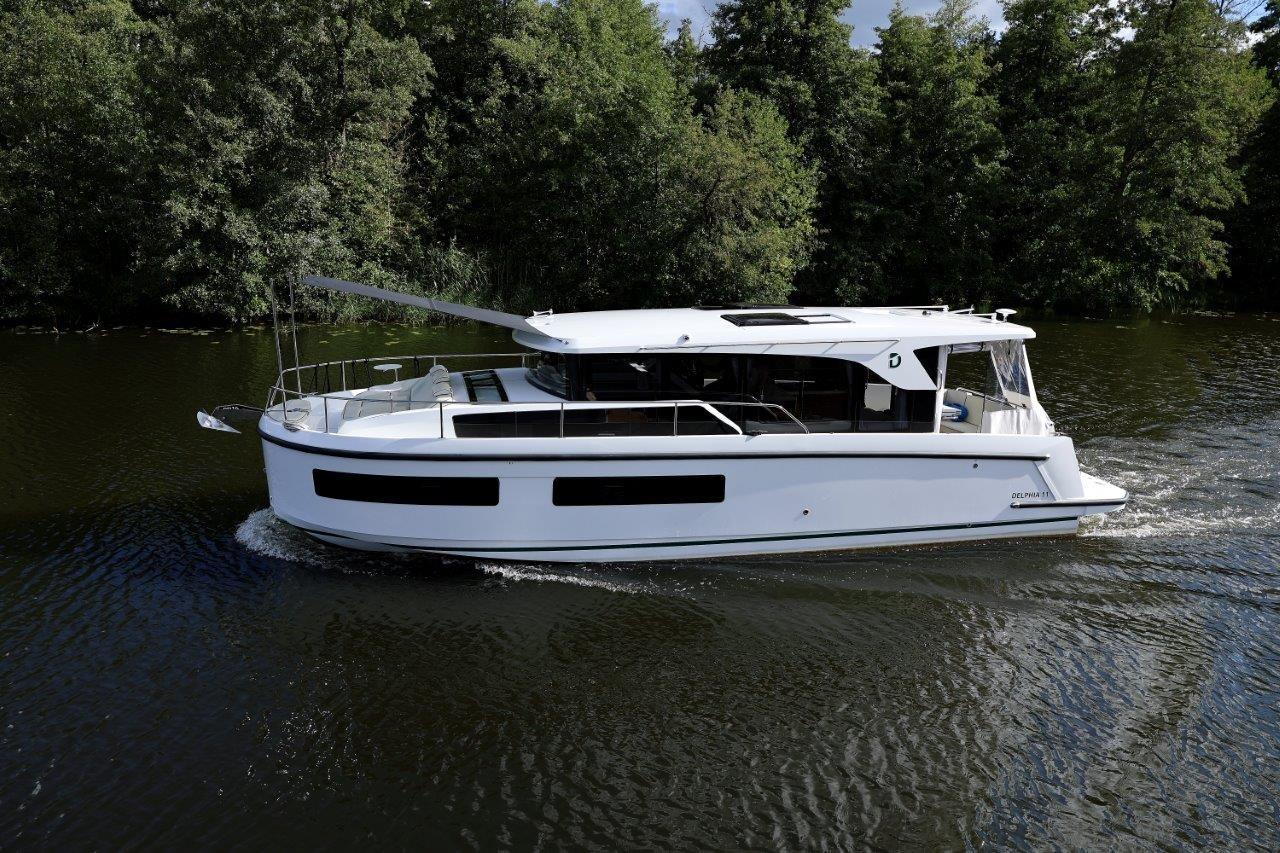 2025 Delphia D11 SEDAN cruising on a serene river, surrounded by lush greenery.