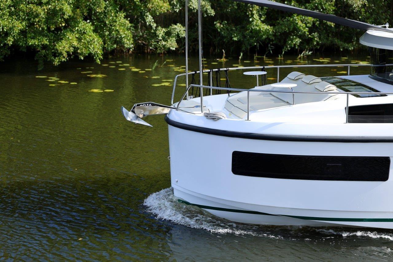 2025 Delphia D11 SEDAN cruising on a serene river with lush greenery.