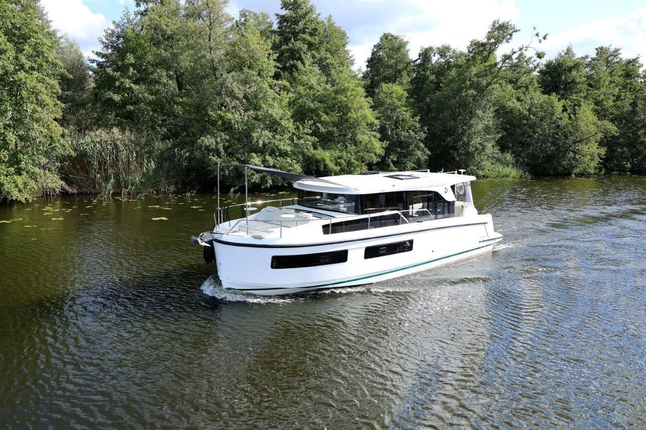 2025 Delphia D11 SEDAN cruising on a serene river surrounded by lush greenery.