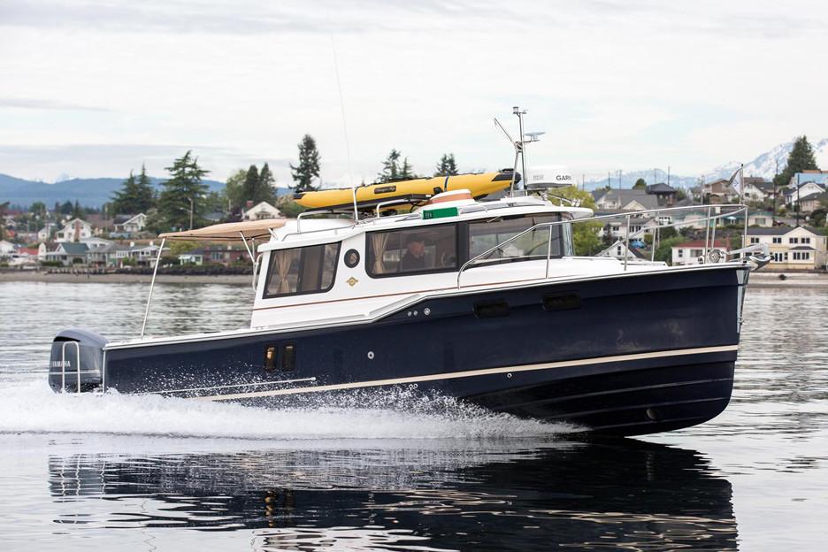 Manufacturer Provided Image: 2018 Ranger Tugs R-27 boat cruising on a calm lake near a residential area.