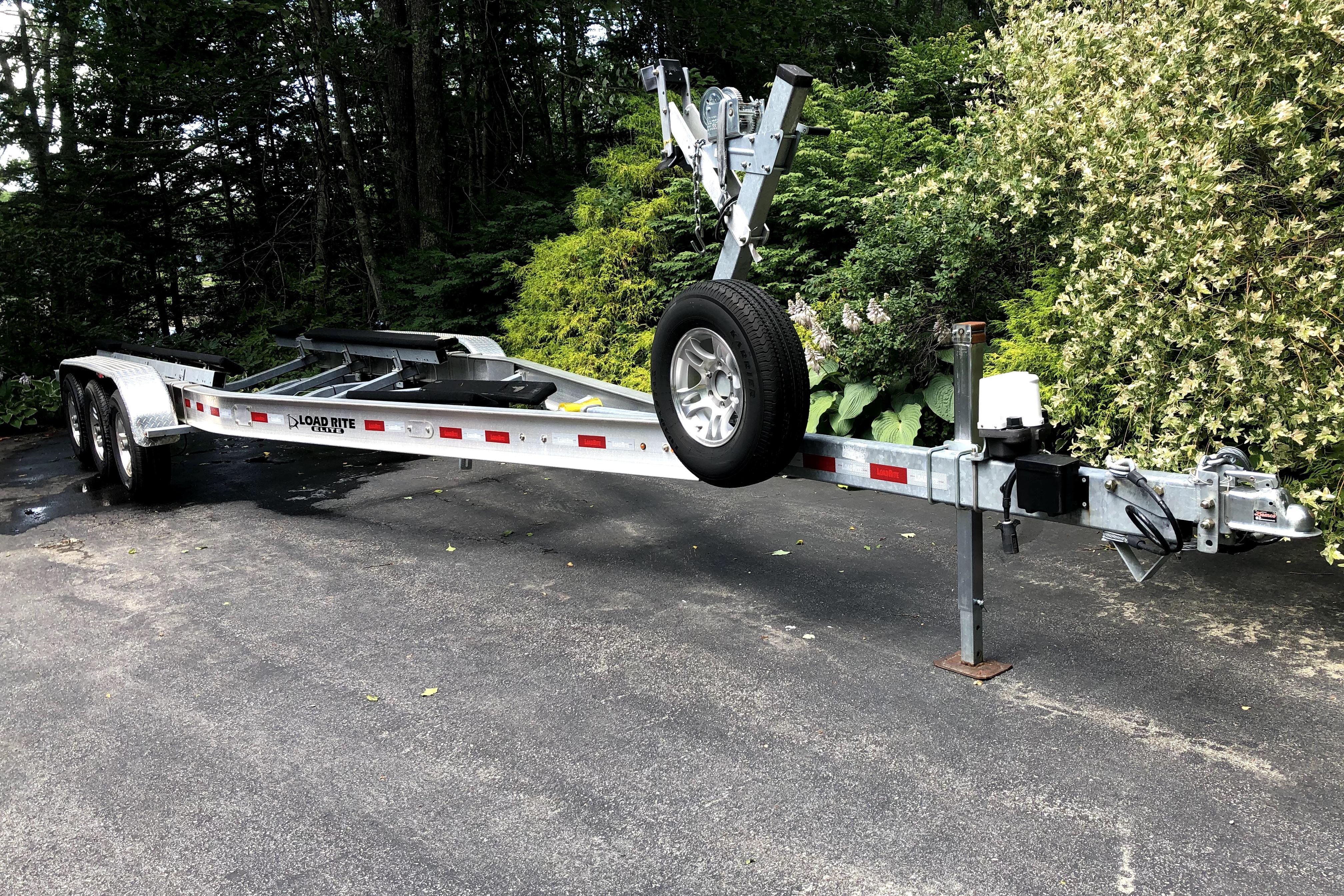 2018 Ranger Tugs R-27 boat trailer parked on driveway, surrounded by lush greenery.