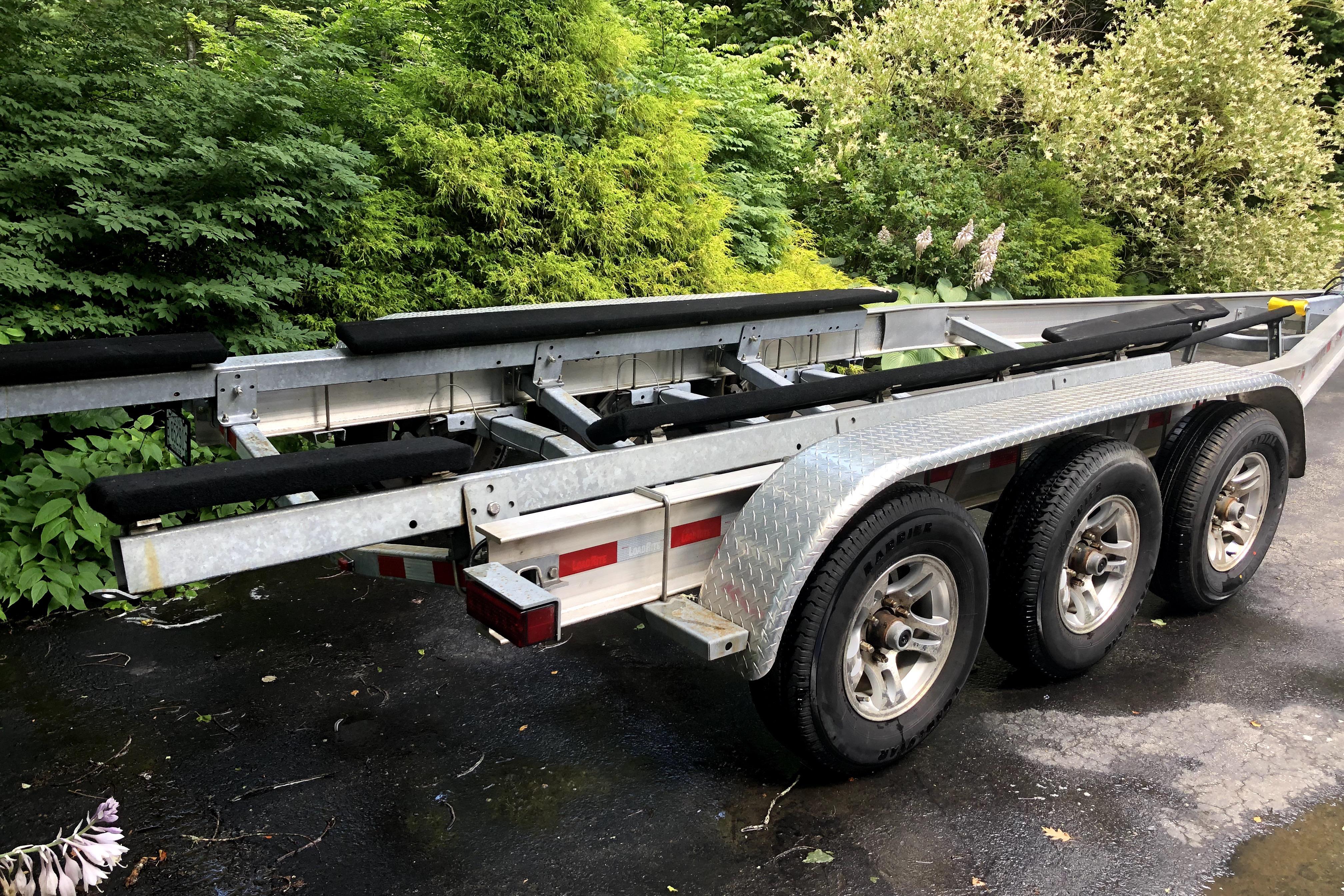 Triple-axle boat trailer for 2018 Ranger Tugs R-27, parked on a driveway.