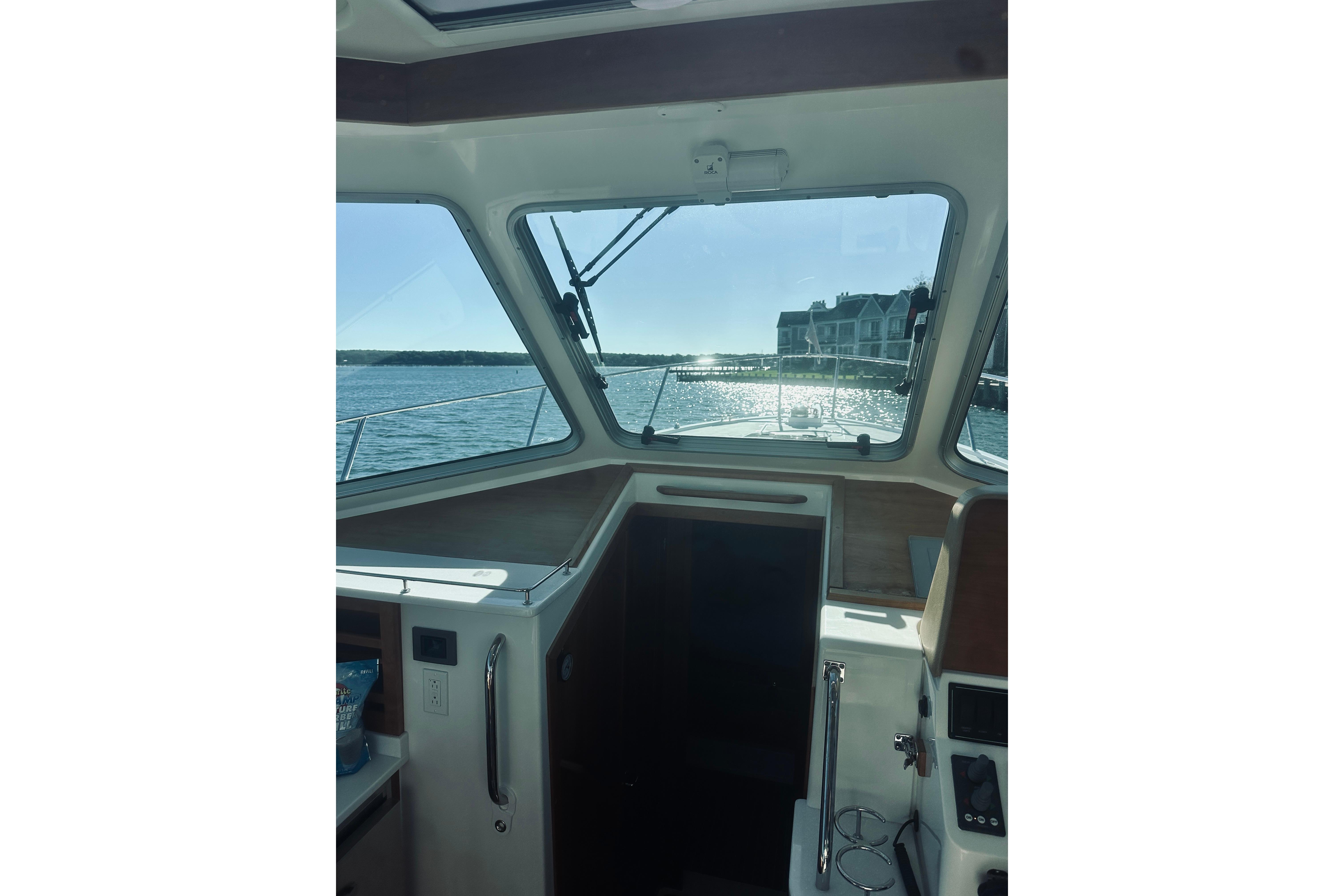 Interior view from a 2021 Back Cove 37 boat, overlooking a sunny waterfront.