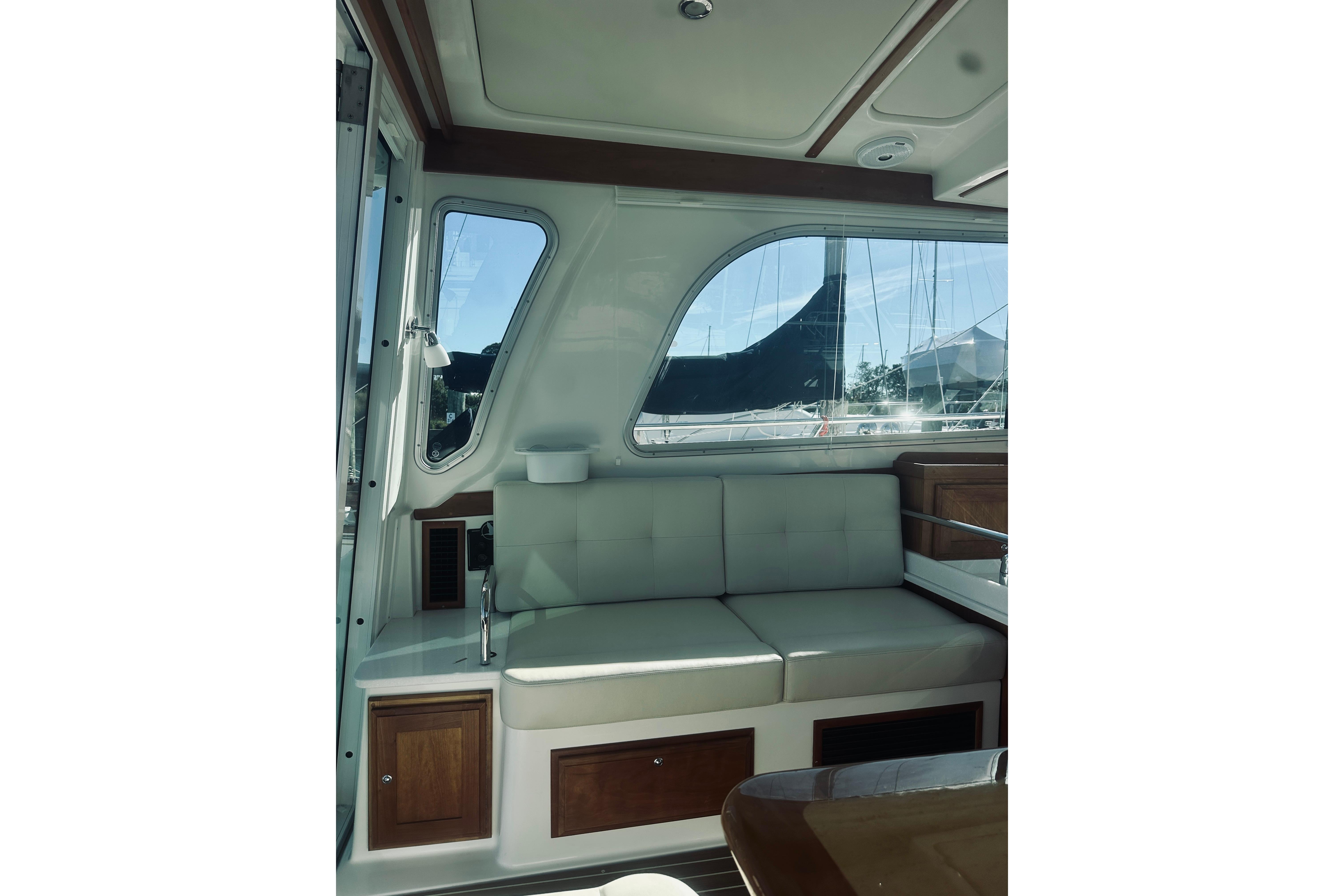 Interior of 2021 Back Cove 37 yacht with cushioned seating and large windows.