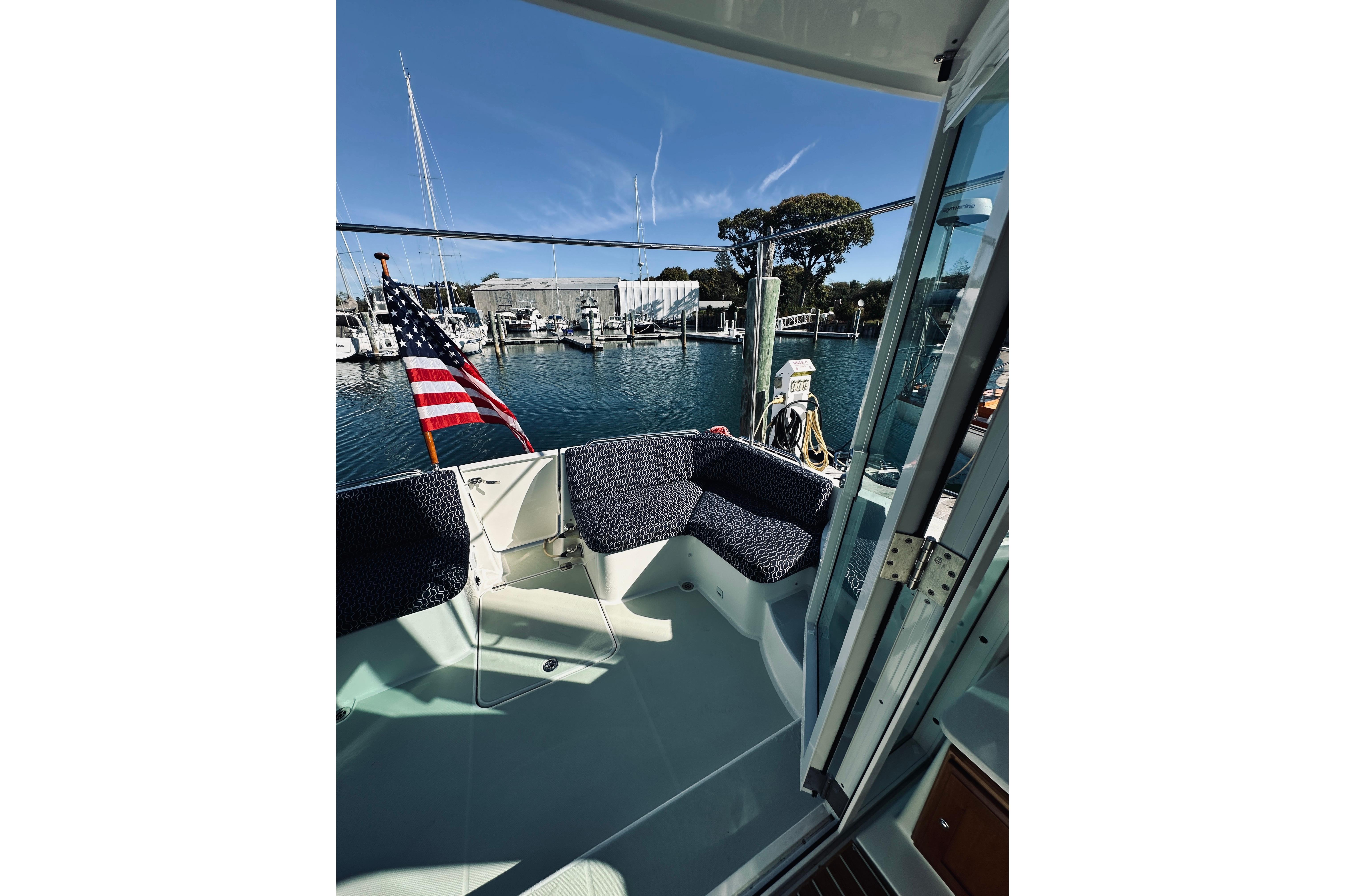 2021 Back Cove 37 boat deck with seating, American flag, and marina view.