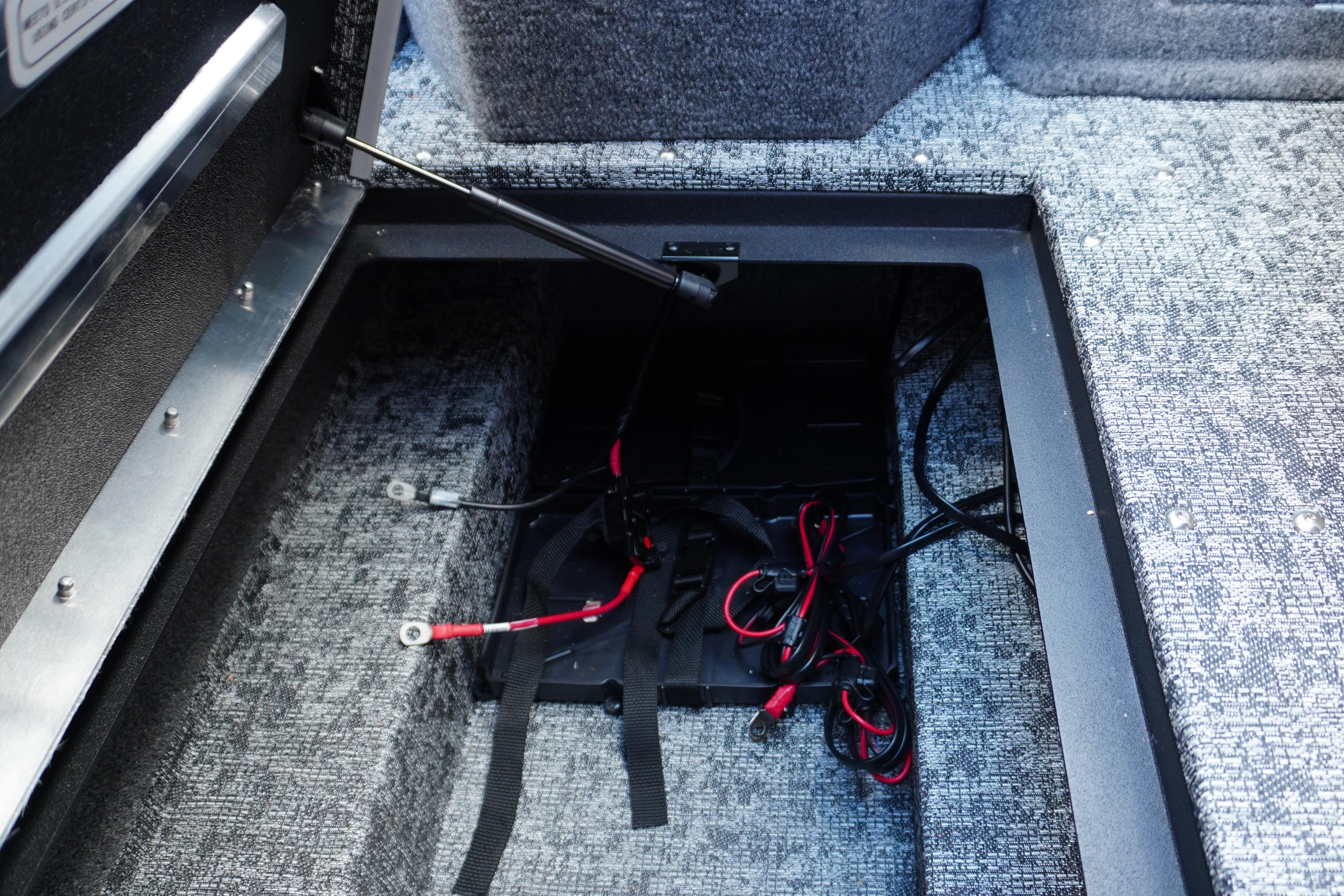 2026 Tracker Targa V-18 WT boat battery compartment with wiring and carpeted interior.