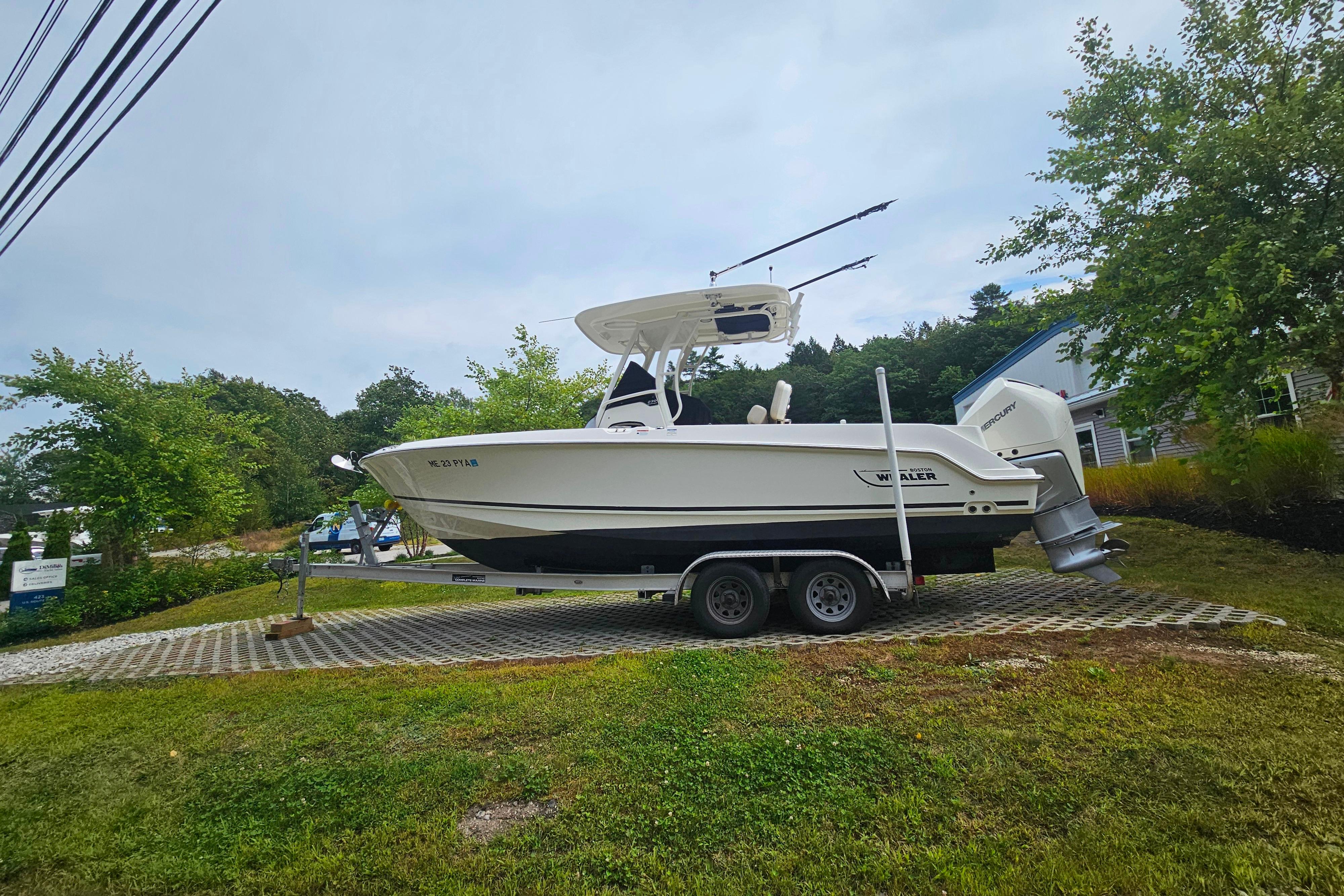 2019 Boston Whaler 230 Outrage boat on trailer, parked outdoors with trees in background.