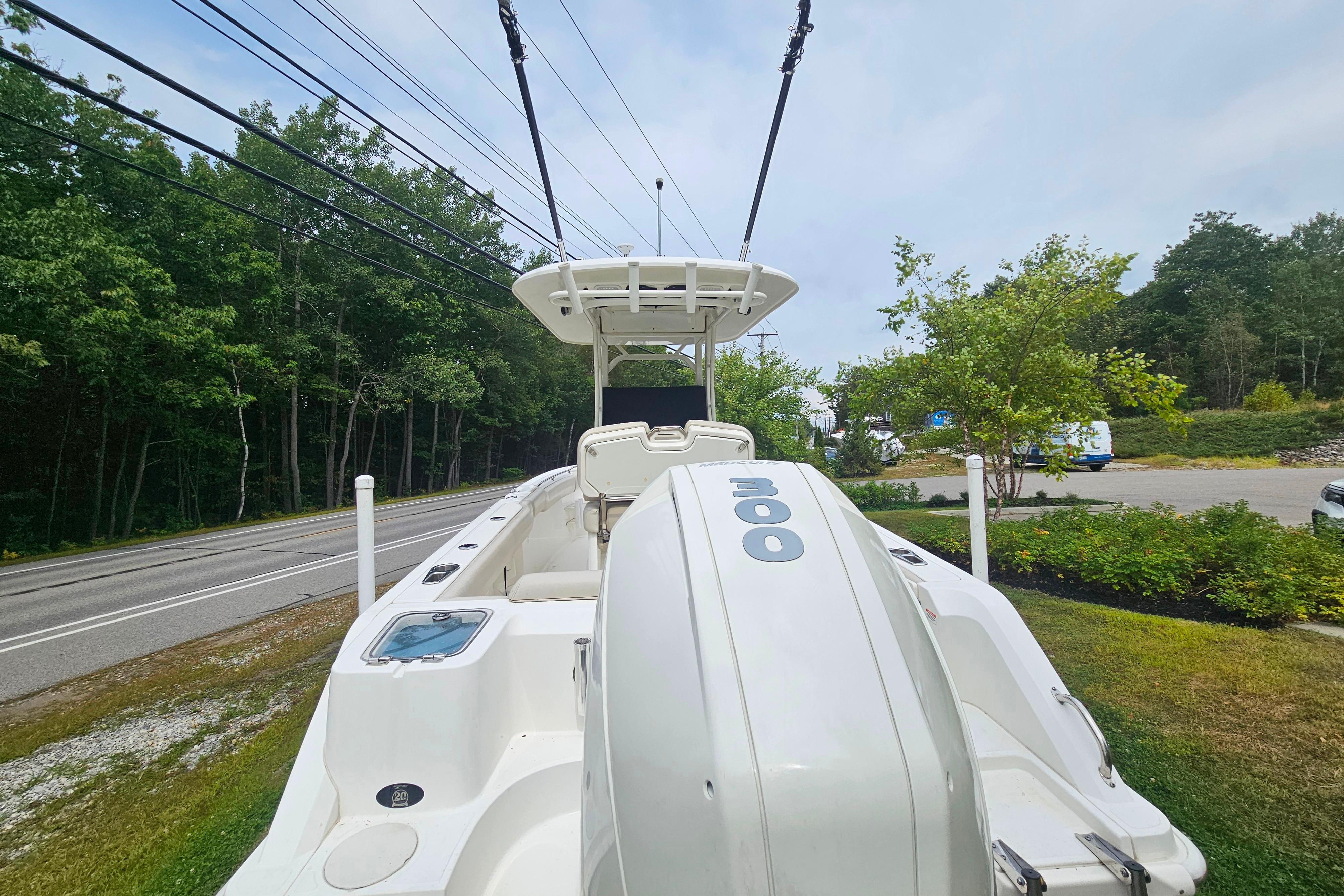 2019 Boston Whaler 230 Outrage boat with powerful outboard motor, parked near a road.