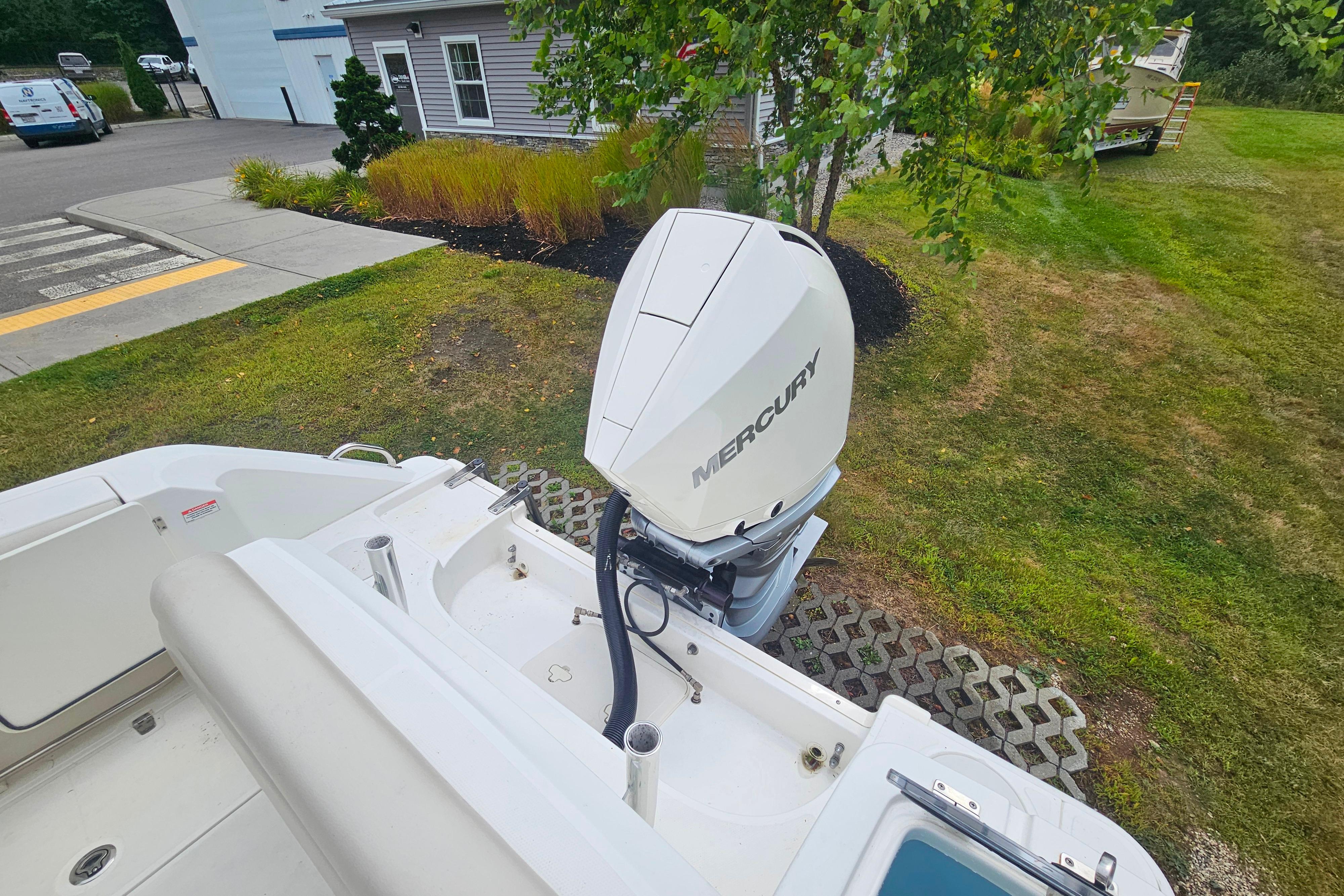 2019 Boston Whaler 230 Outrage with Mercury outboard engine, parked on grassy area.