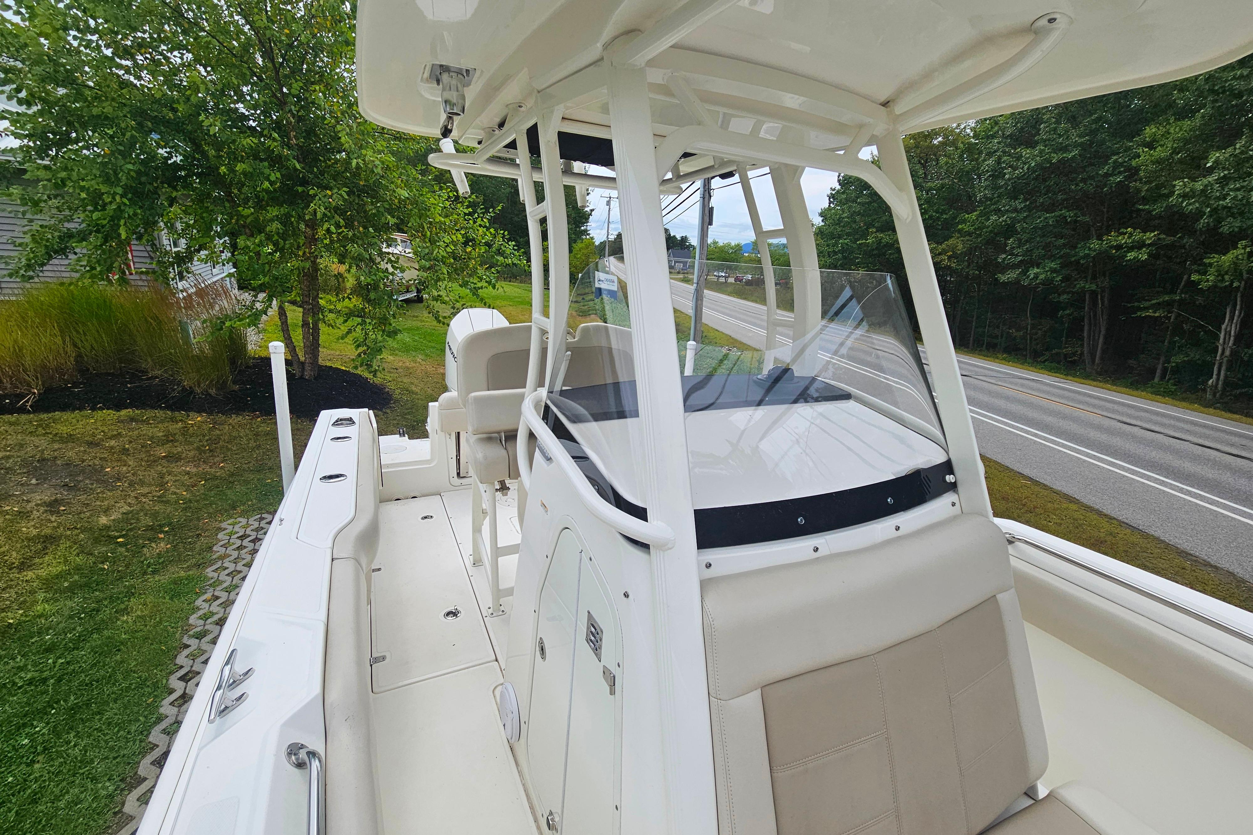 2019 Boston Whaler 230 Outrage boat with sleek design, parked near a road and greenery.