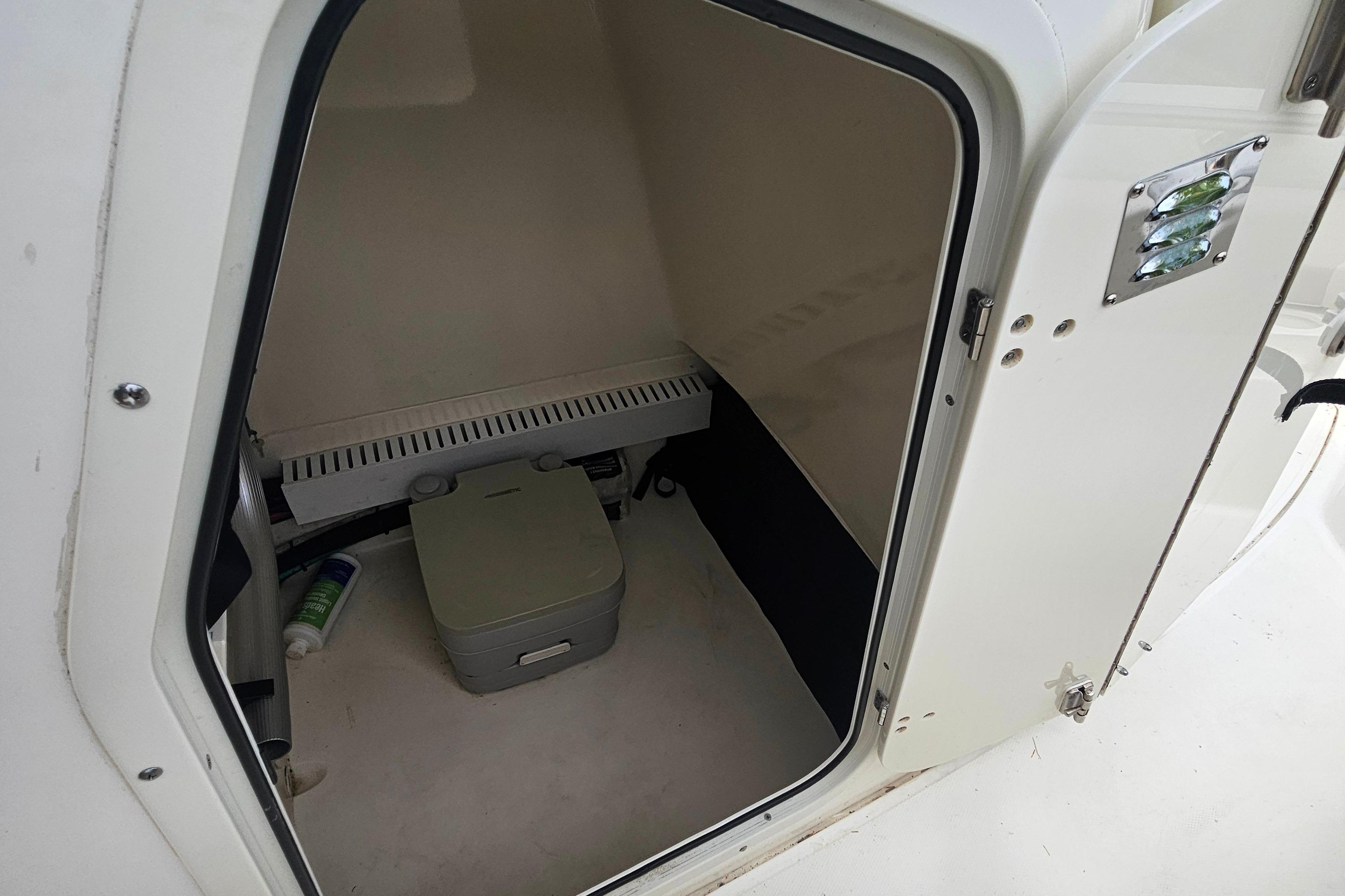 2019 Boston Whaler 230 Outrage boat interior with storage compartment and portable toilet.