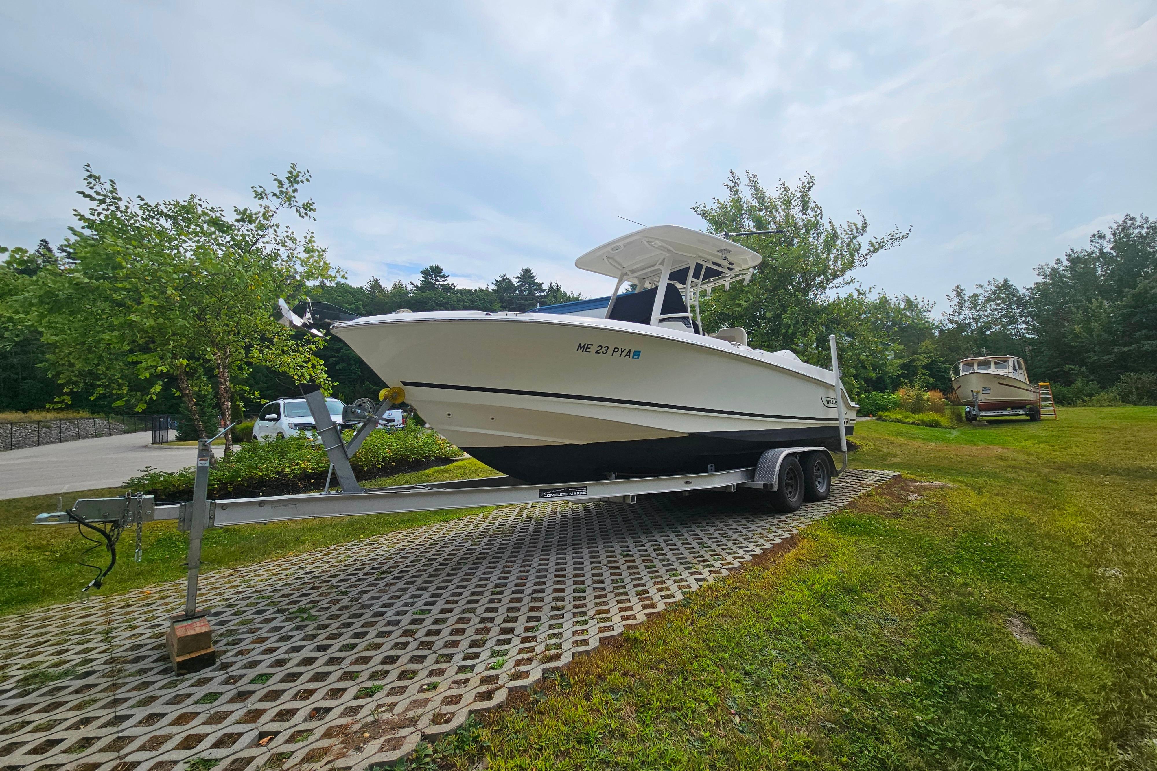 2019 Boston Whaler 230 Outrage boat on trailer, parked on grassy area.