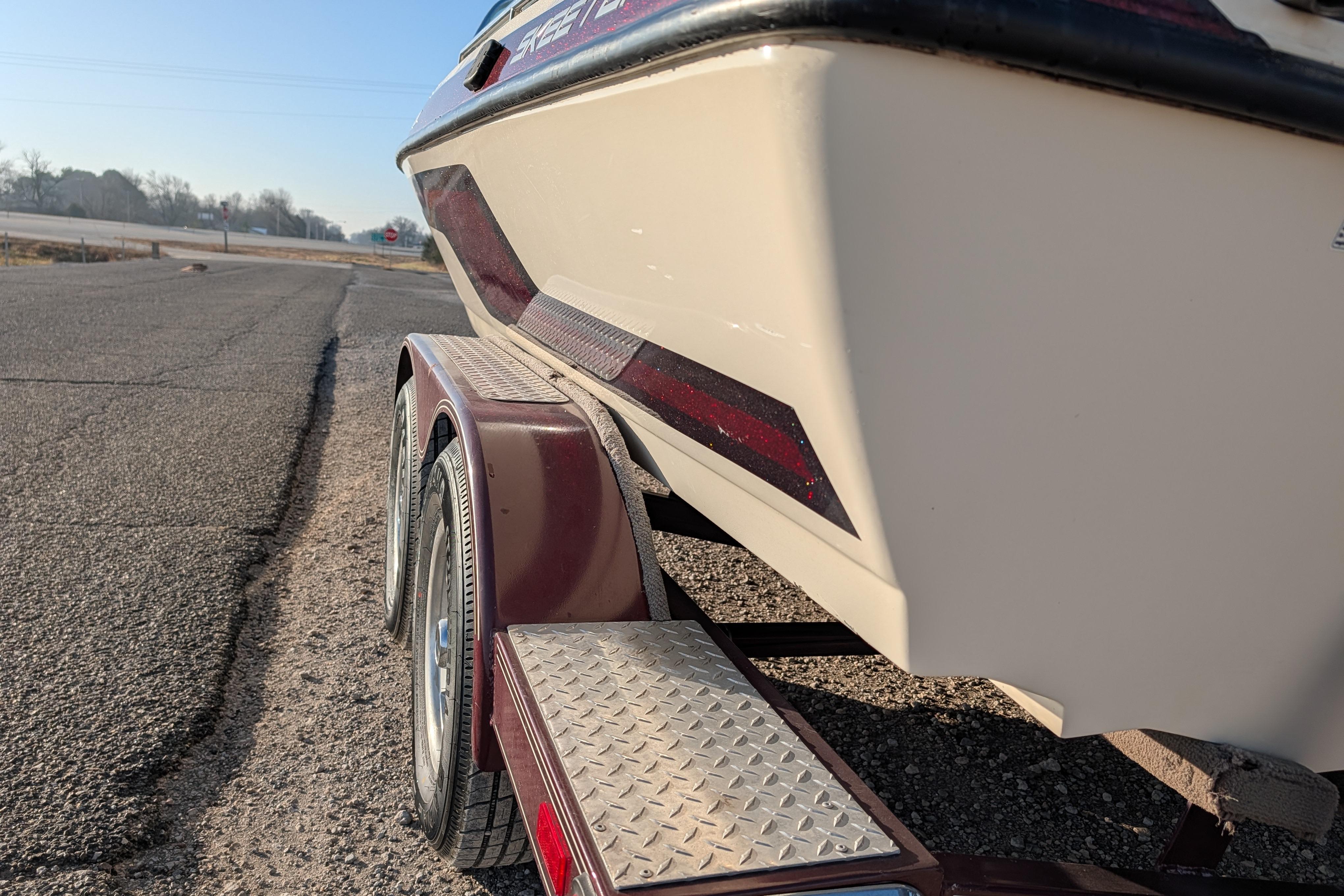 2009 Skeeter SL1900 boat on trailer, parked on roadside under clear sky.