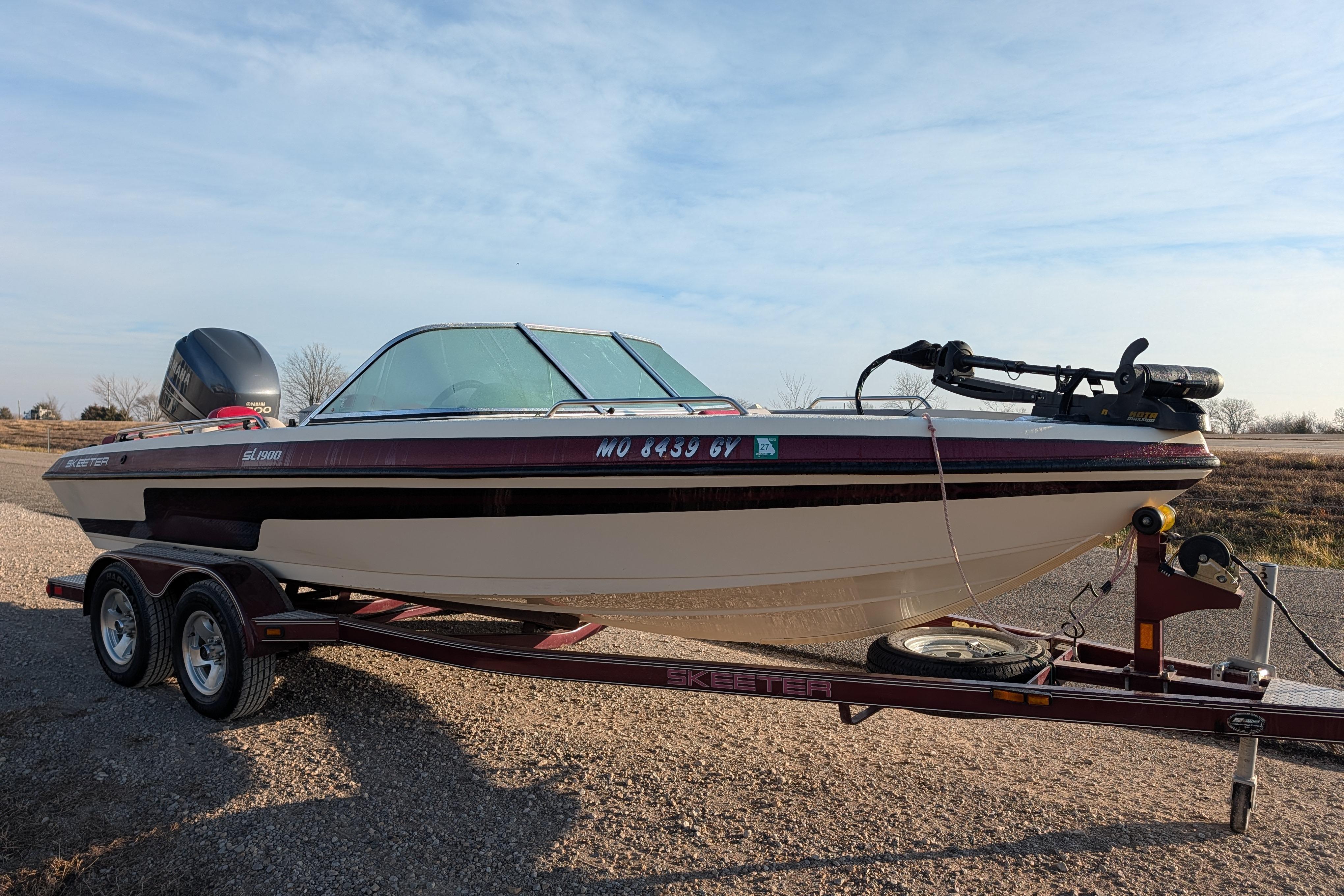 2009 Skeeter SL1900 boat on trailer, parked outdoors under clear sky.