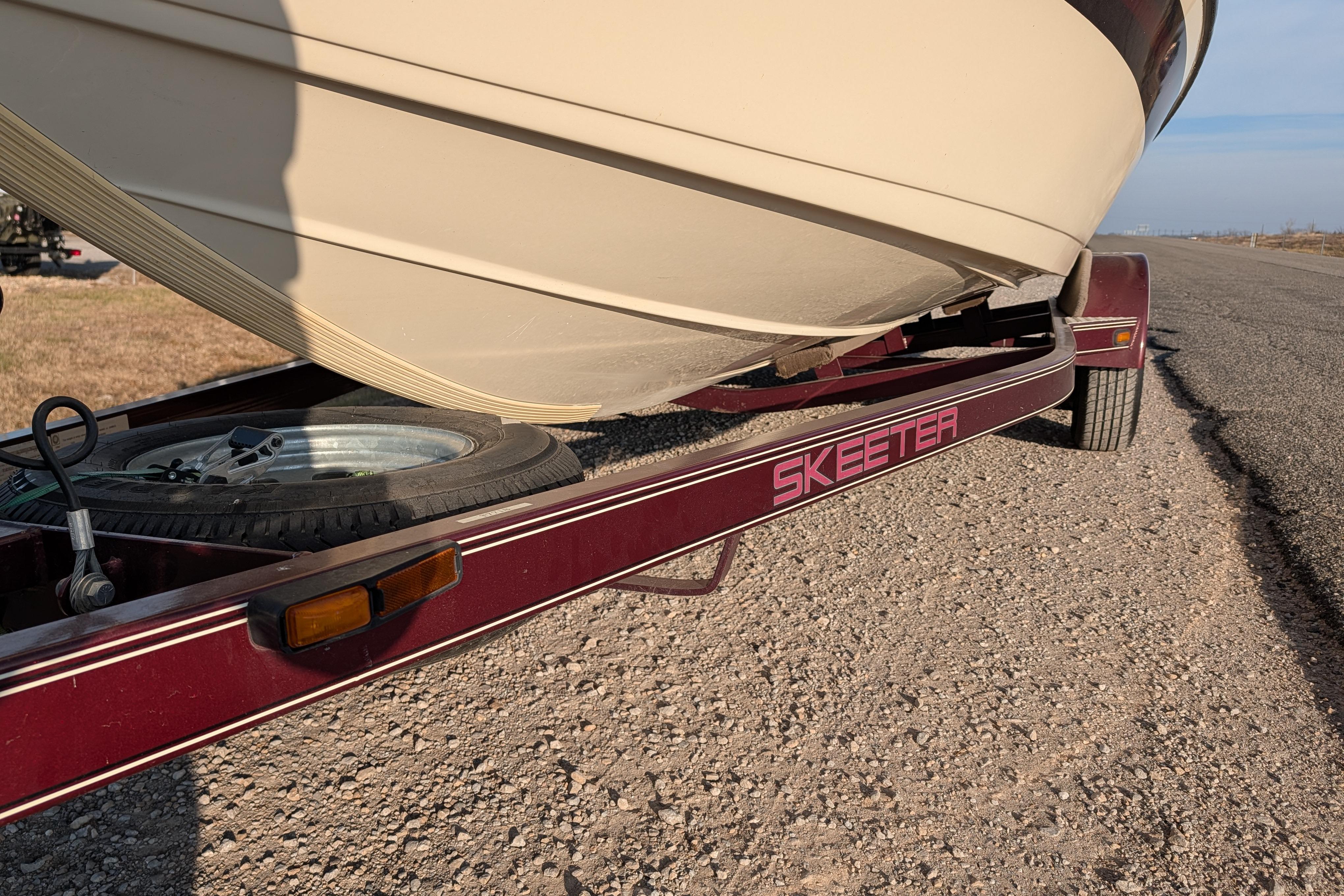2009 Skeeter SL1900 boat on a red trailer, parked on a gravel road.