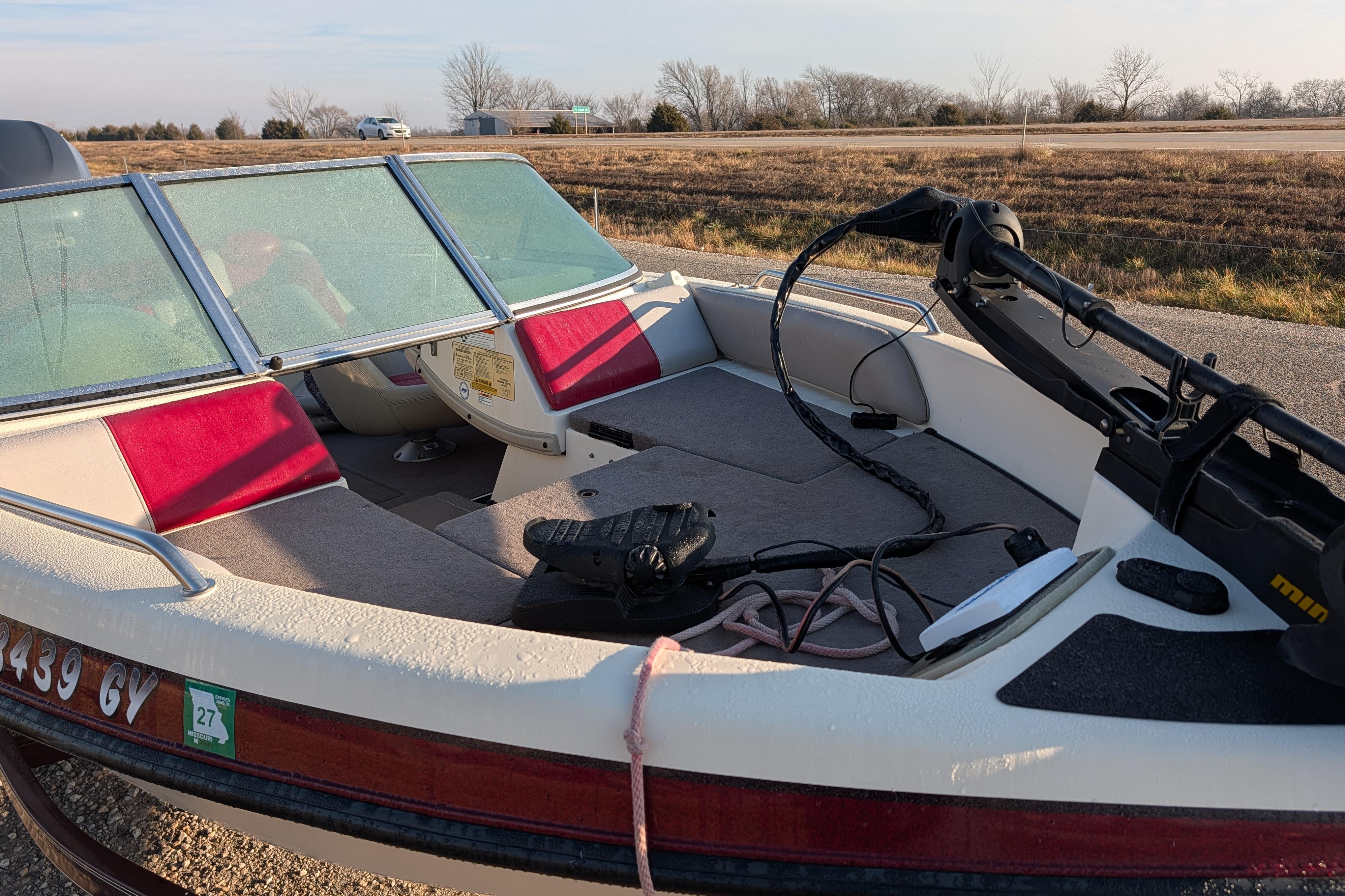 2009 Skeeter SL1900 boat with red and white interior, parked on roadside.