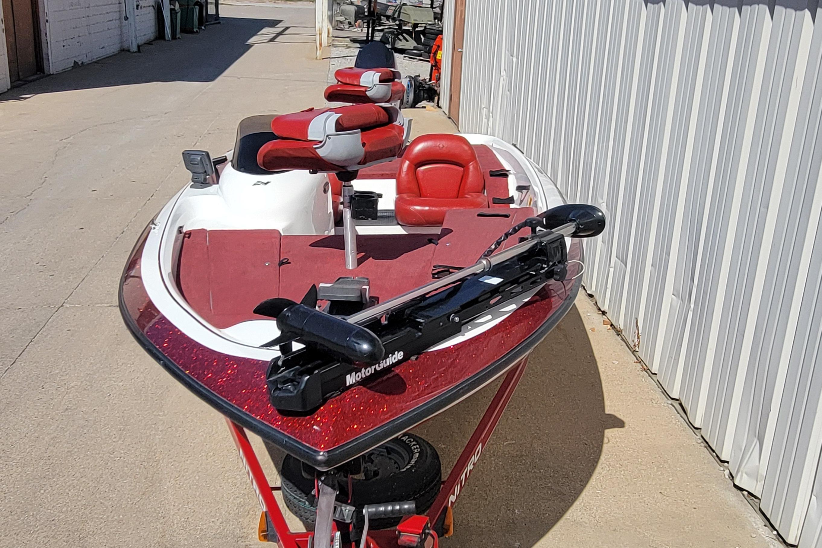 2000 Nitro 640LX boat with red and white seats, parked outdoors.