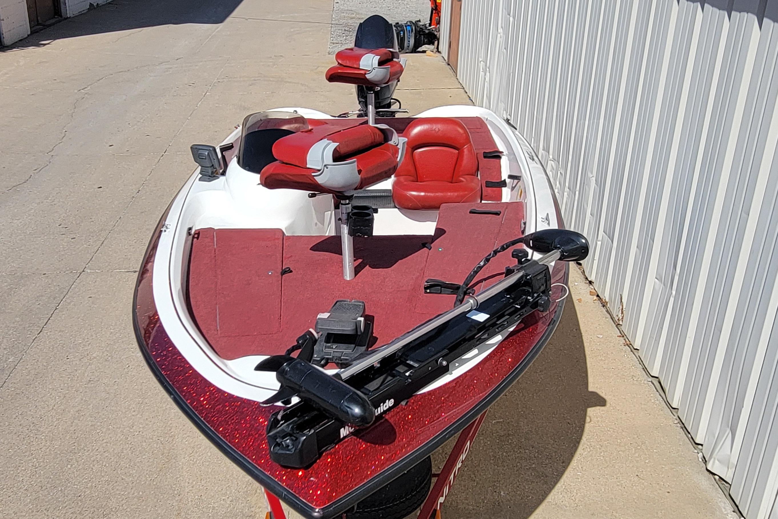 2000 Nitro 640LX boat with red and white seating, parked beside a building.