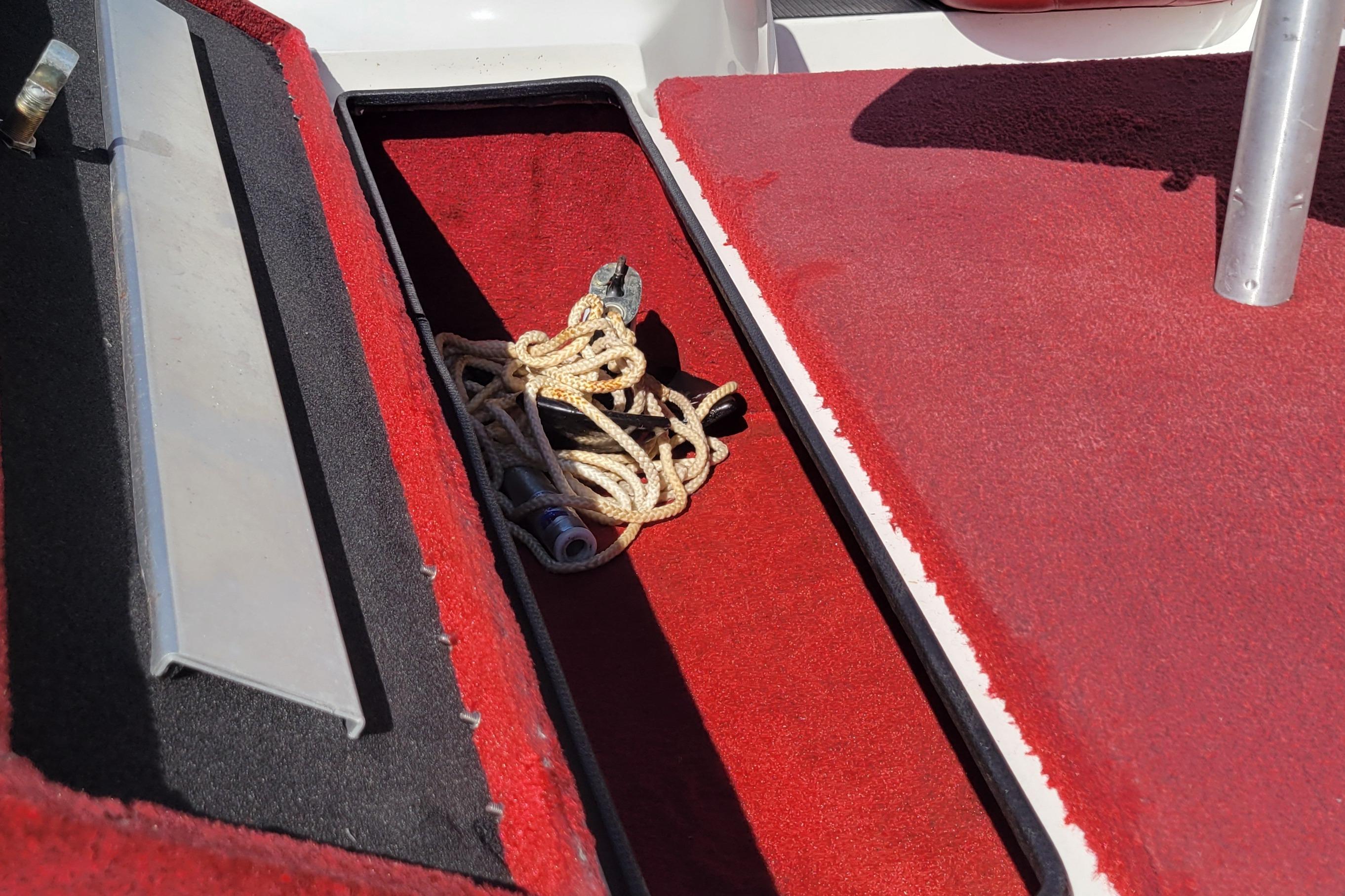 Open storage compartment on 2000 Nitro 640LX boat with red carpet and rope inside.