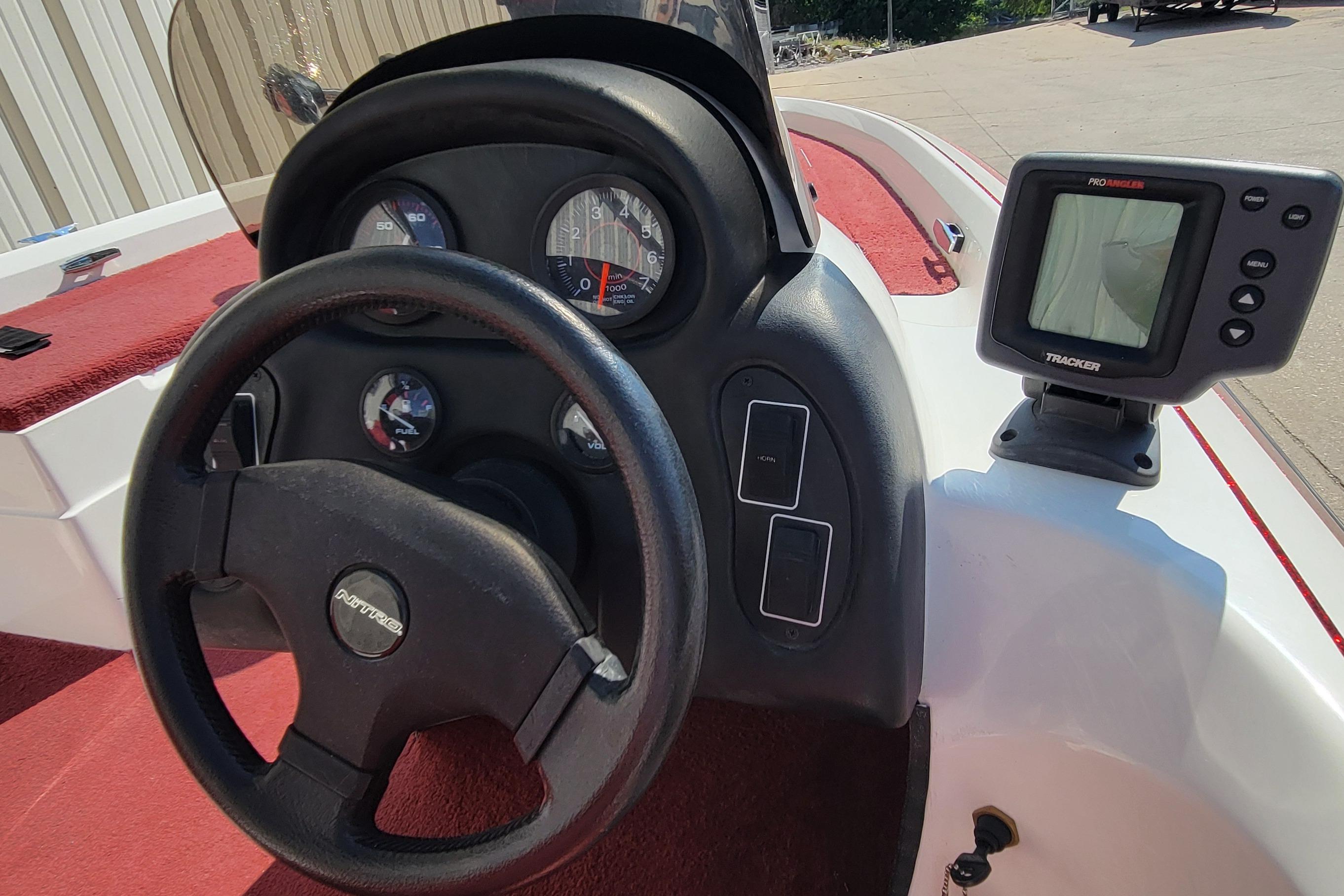 Steering wheel and dashboard of a 2000 Nitro 640LX boat with gauges and fish finder.