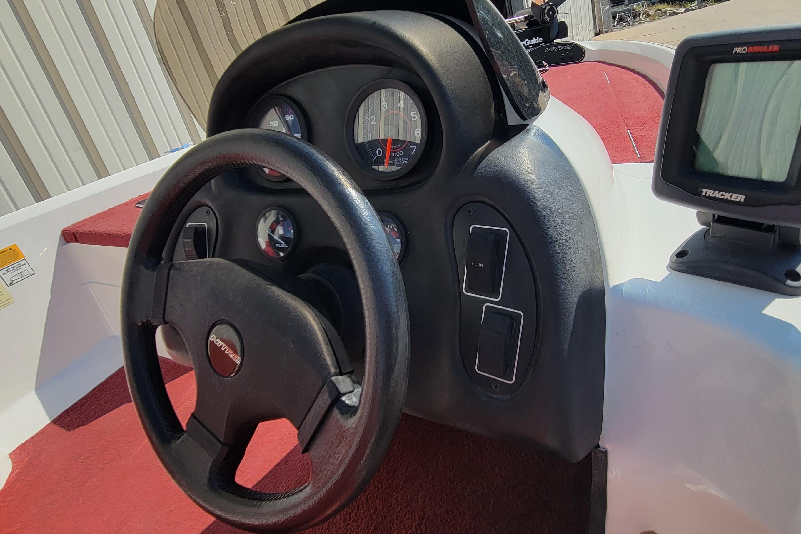 Steering wheel and dashboard of a 2000 Nitro 640LX boat with gauges and controls.