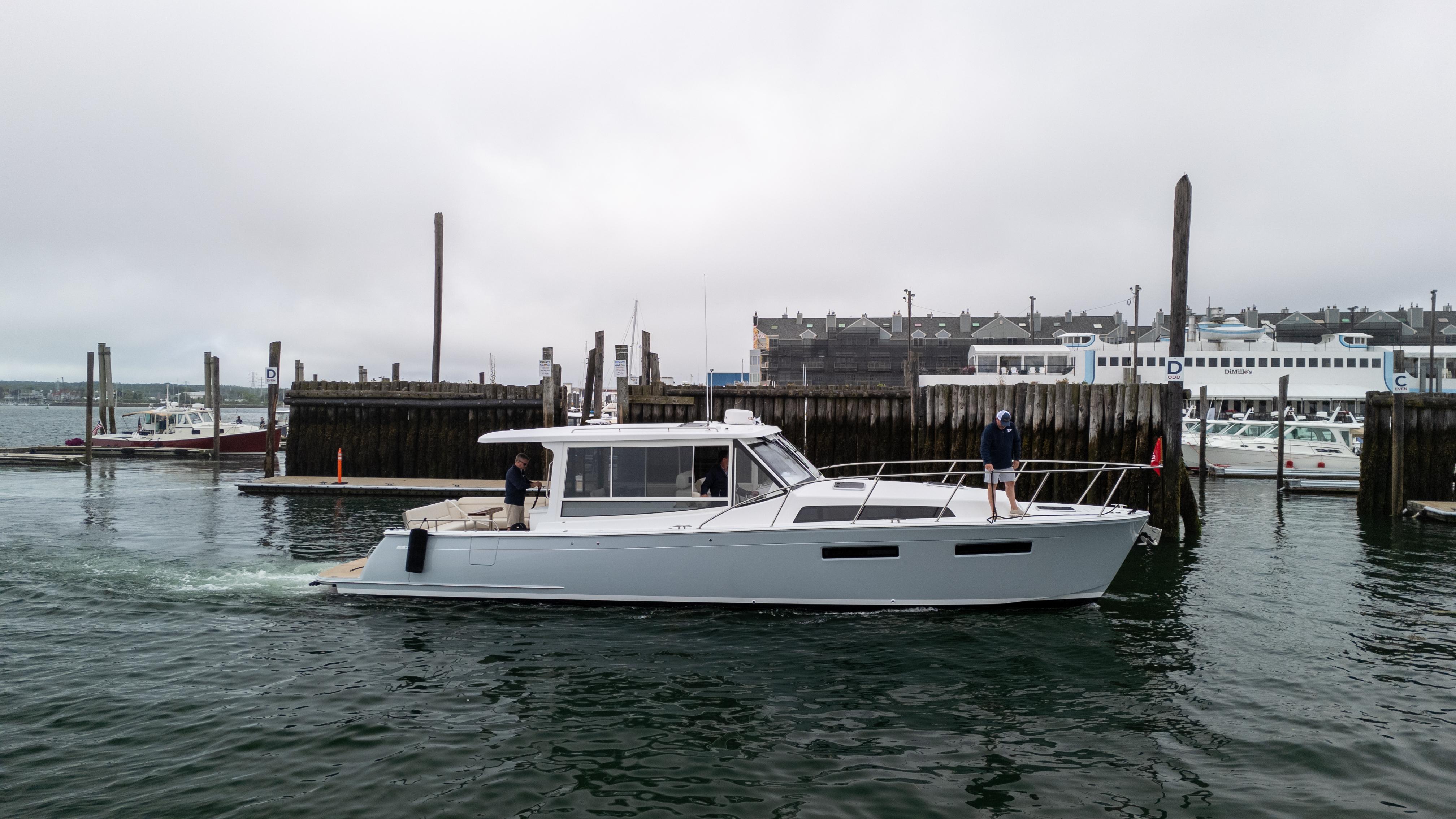 2026 MJM 47R yacht cruising near a marina under overcast skies.
