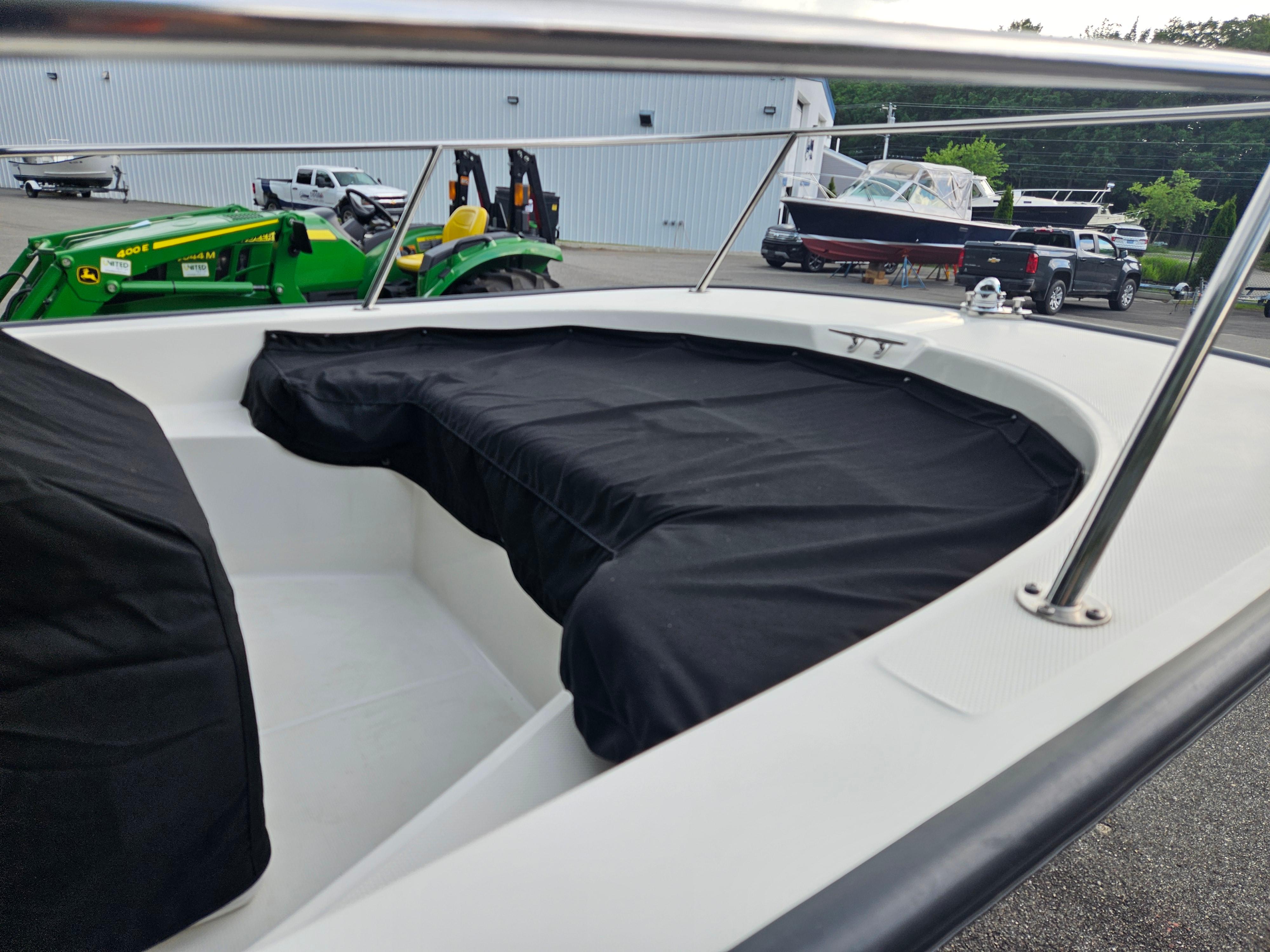 2008 Boston Whaler 170 Montauk boat with black cover, parked near green tractor.