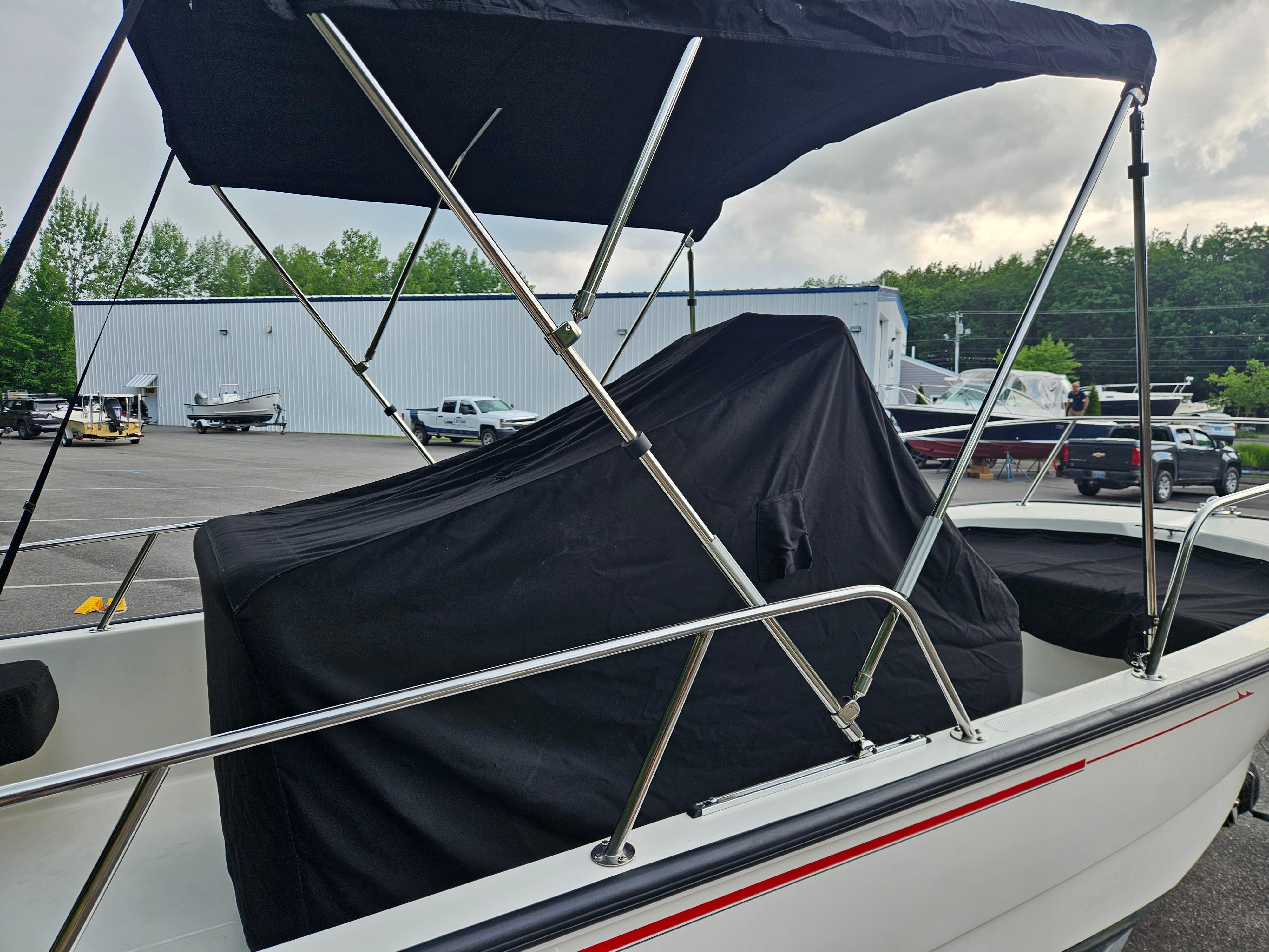 2008 Boston Whaler 170 Montauk boat with cover and canopy in a parking lot.