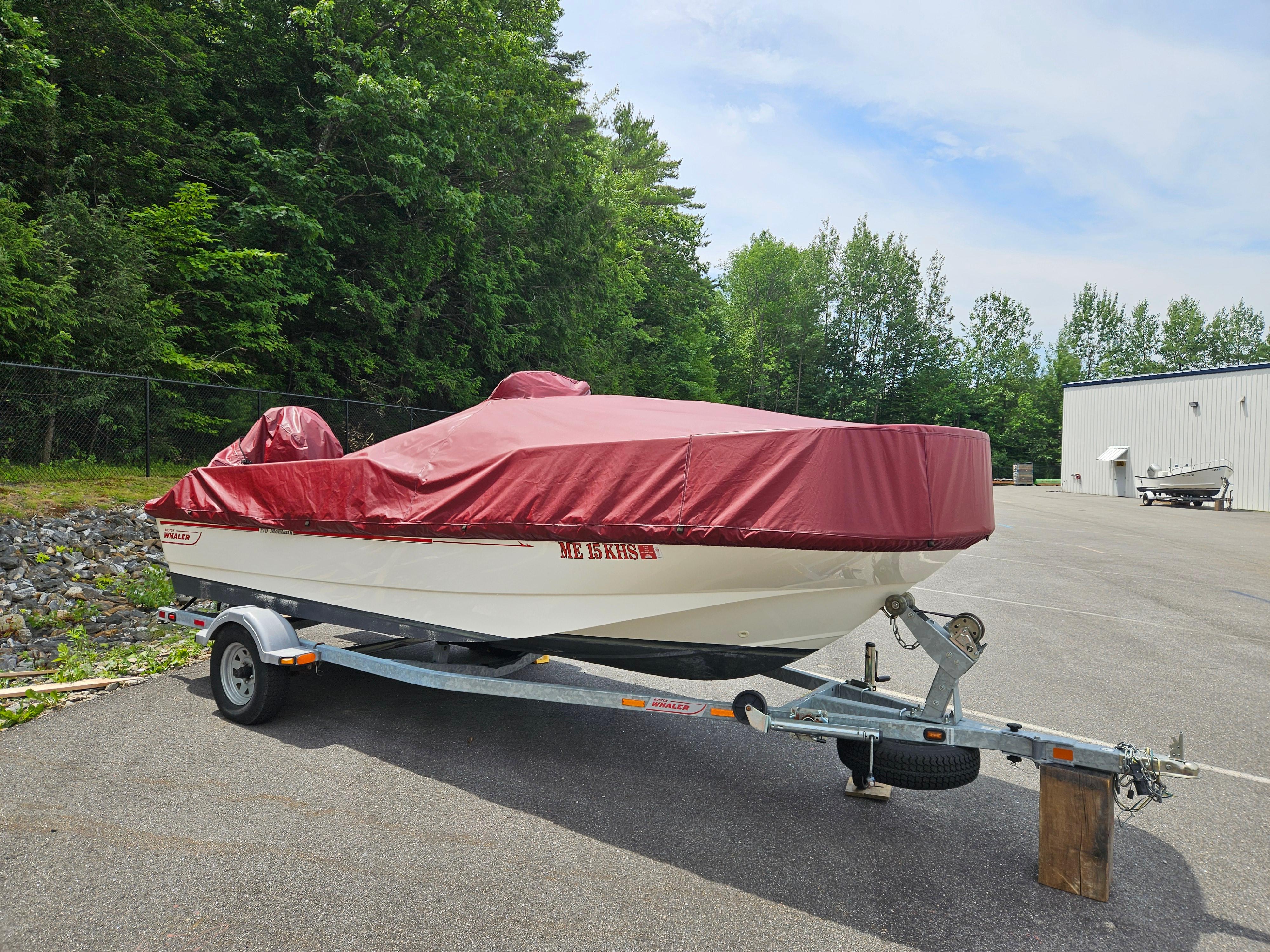 2008 Boston Whaler 170 Montauk boat on trailer with red cover, parked outdoors.