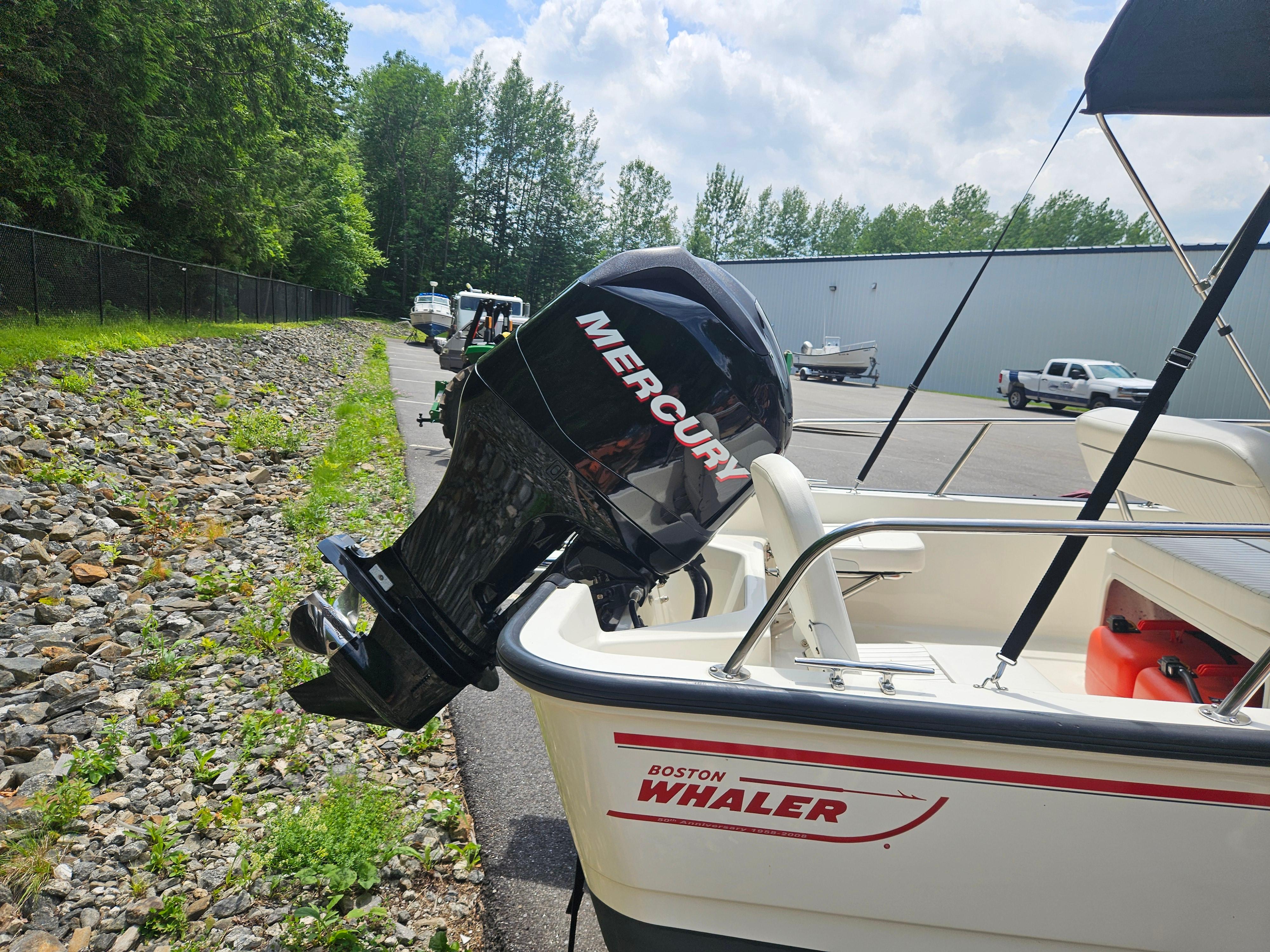 2008 Boston Whaler 170 Montauk with Mercury outboard motor, parked near a rocky path.