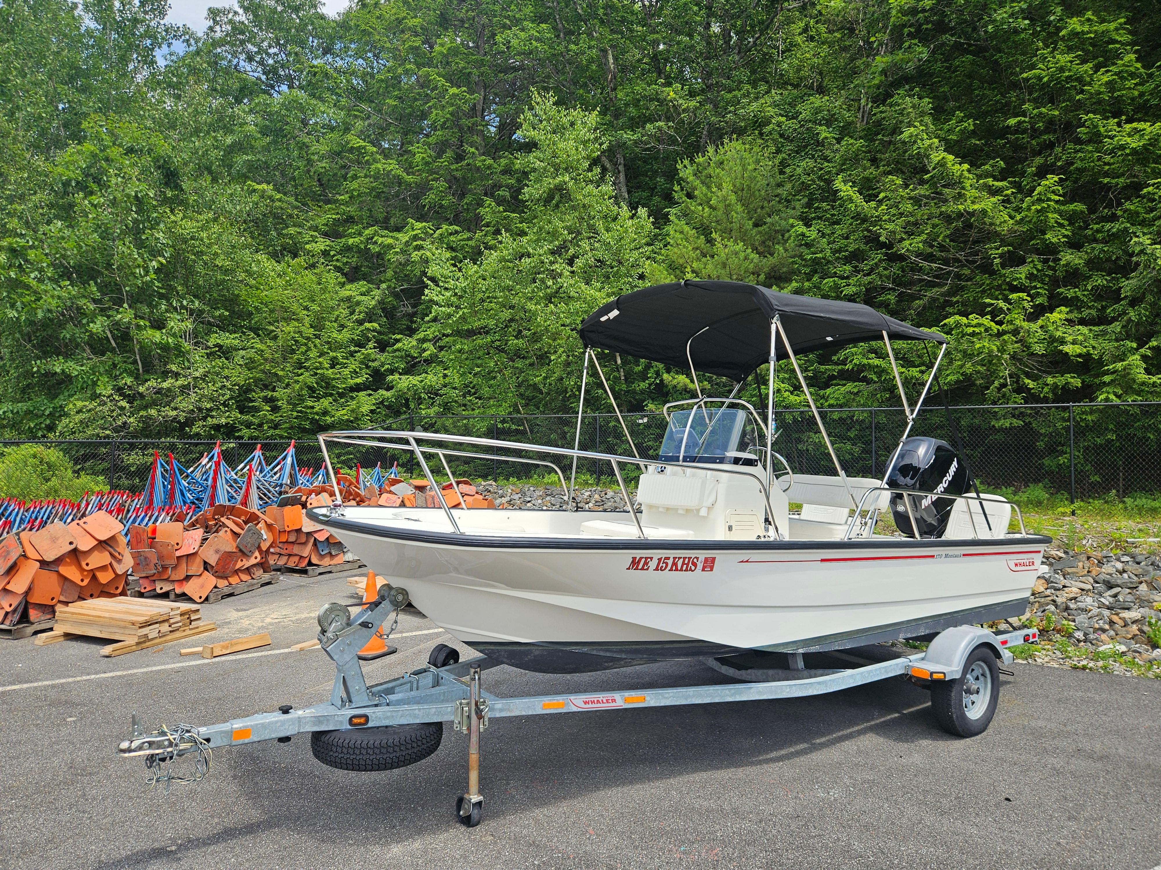 2008 Boston Whaler 170 Montauk boat on trailer, parked near forested area.