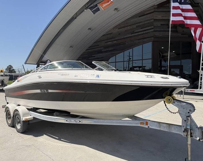 2007 Sea Ray 195 Sport boat on trailer, parked outside a modern building with American flag.