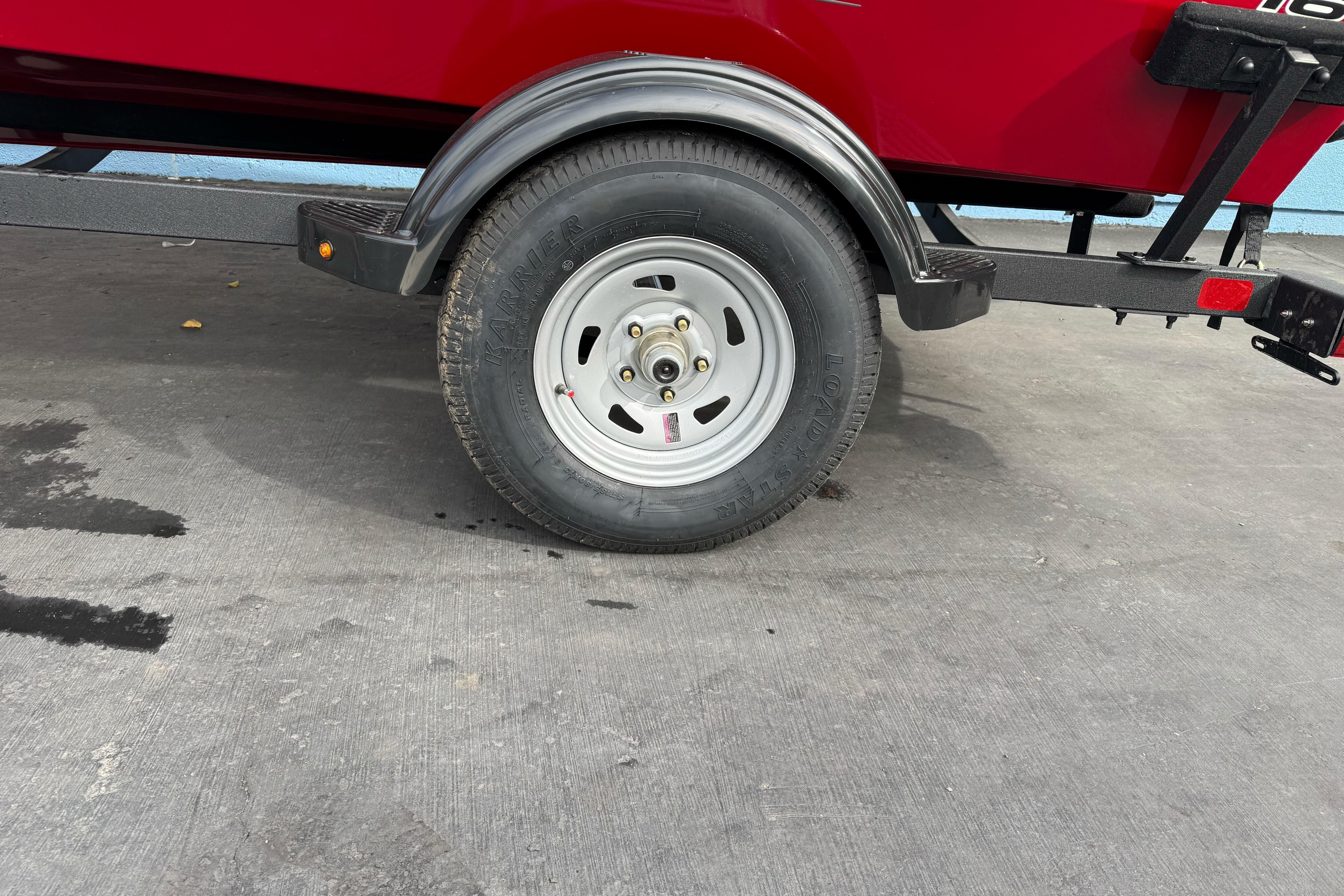 Trailer wheel of 2026 Tracker Super Guide V-16 SC boat on concrete surface.